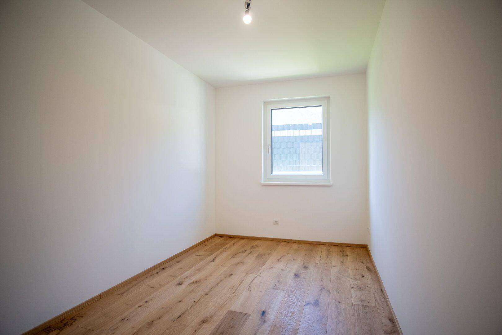 Unmöbliertes Schlafzimmer mit Holzboden und Fenster, ideal für individuelle Gestaltung.