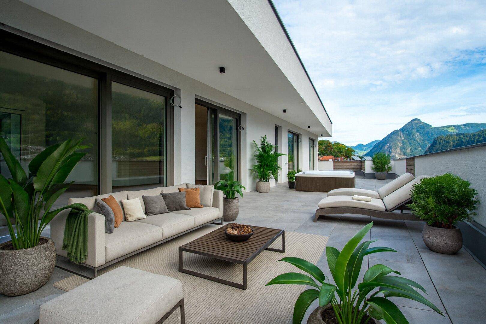 Große möblierte Terrasse mit Whirlpool und Panoramablick auf die Berge.