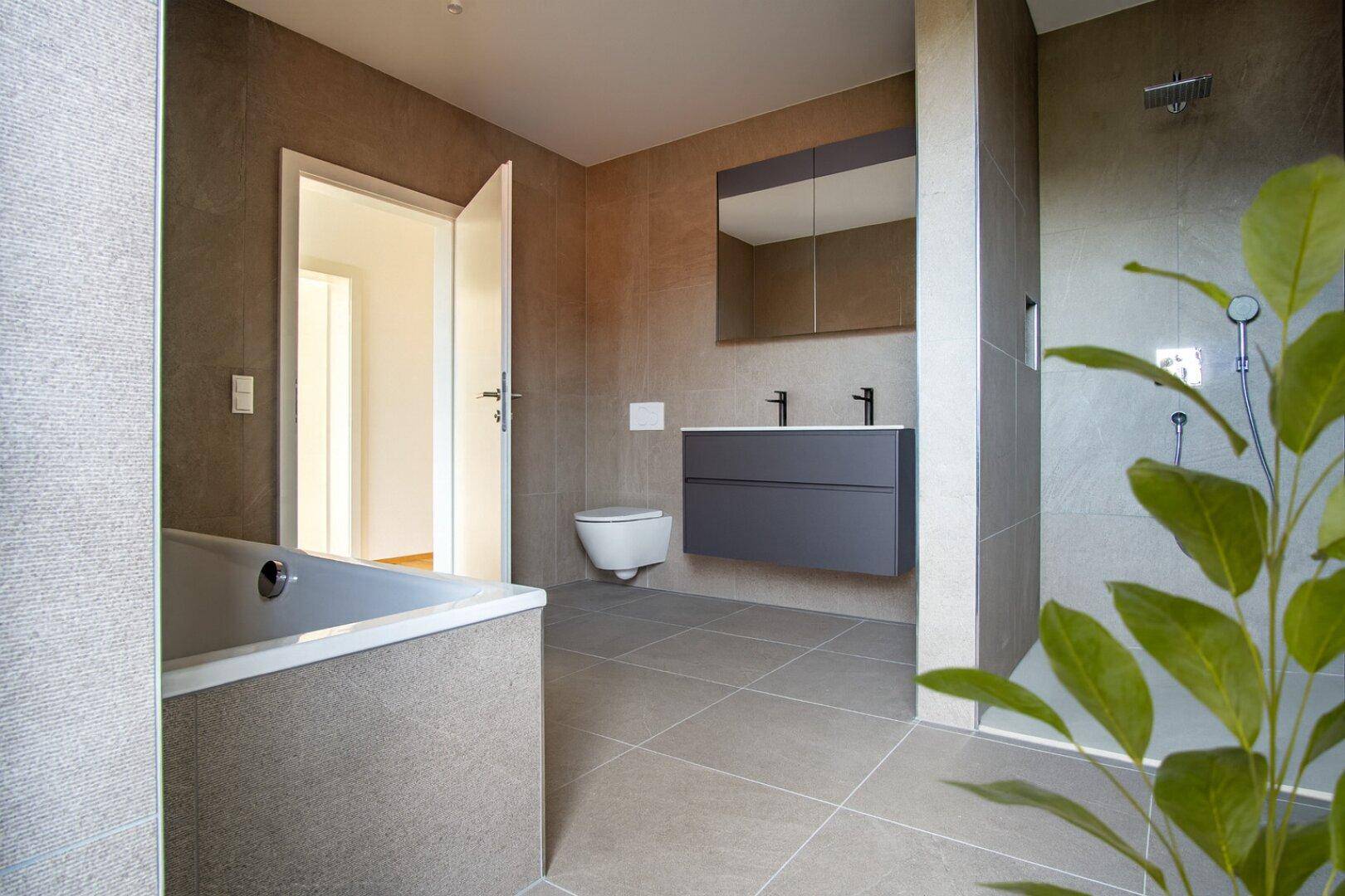 Modernes Badezimmer mit grauen Fliesen, Badewanne und ebenerdiger Dusche.