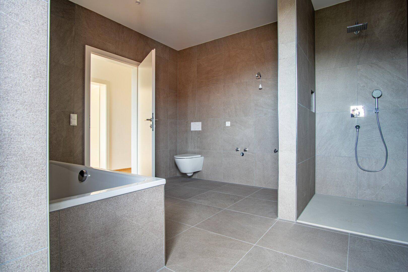 Modernes Badezimmer mit grauen Fliesen, Badewanne und ebenerdiger Dusche.