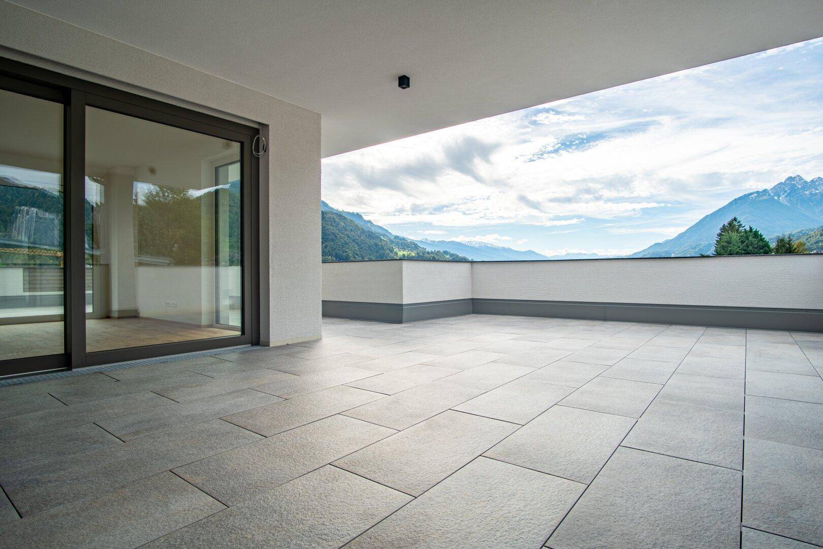 Geräumige Terrasse mit Fliesenboden und weitem Blick auf die umliegende Bergwelt.