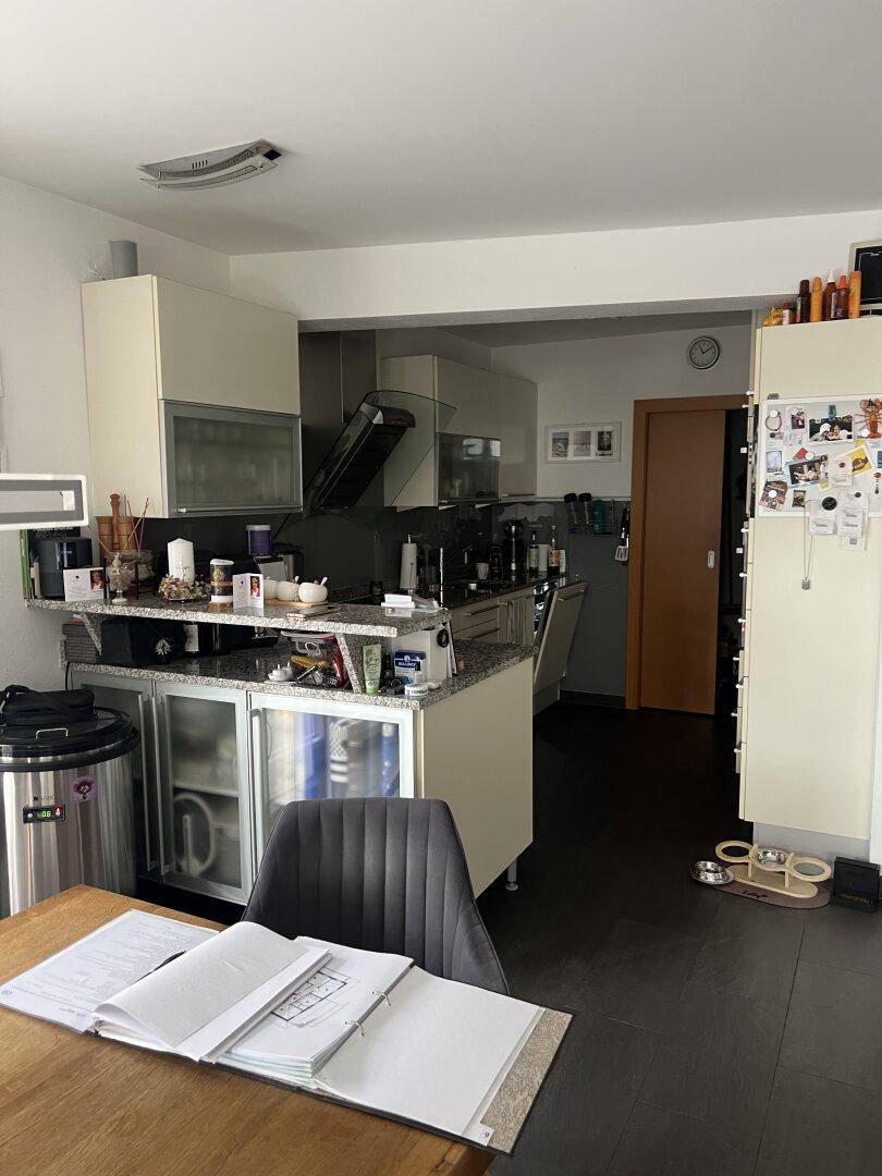 Funktionale Küche mit hellen Schränken, Granitarbeitsplatte und dunklem Fliesenboden.