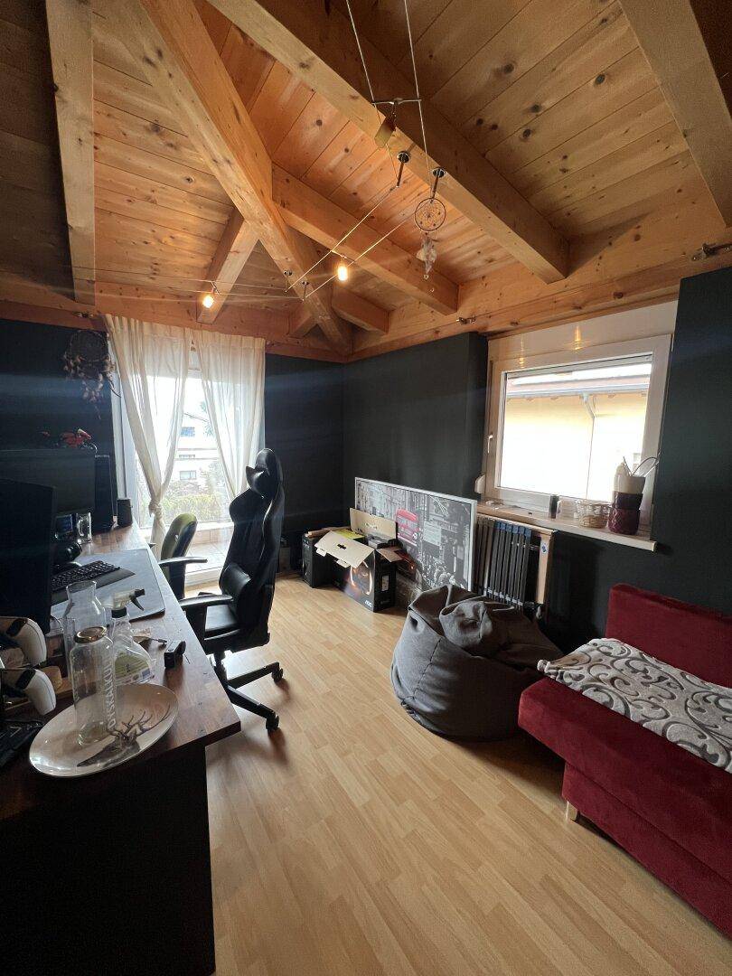 Helles Arbeitszimmer mit Holzbalkendecke, Dachschräge und Parkettboden im Obergeschoss.
