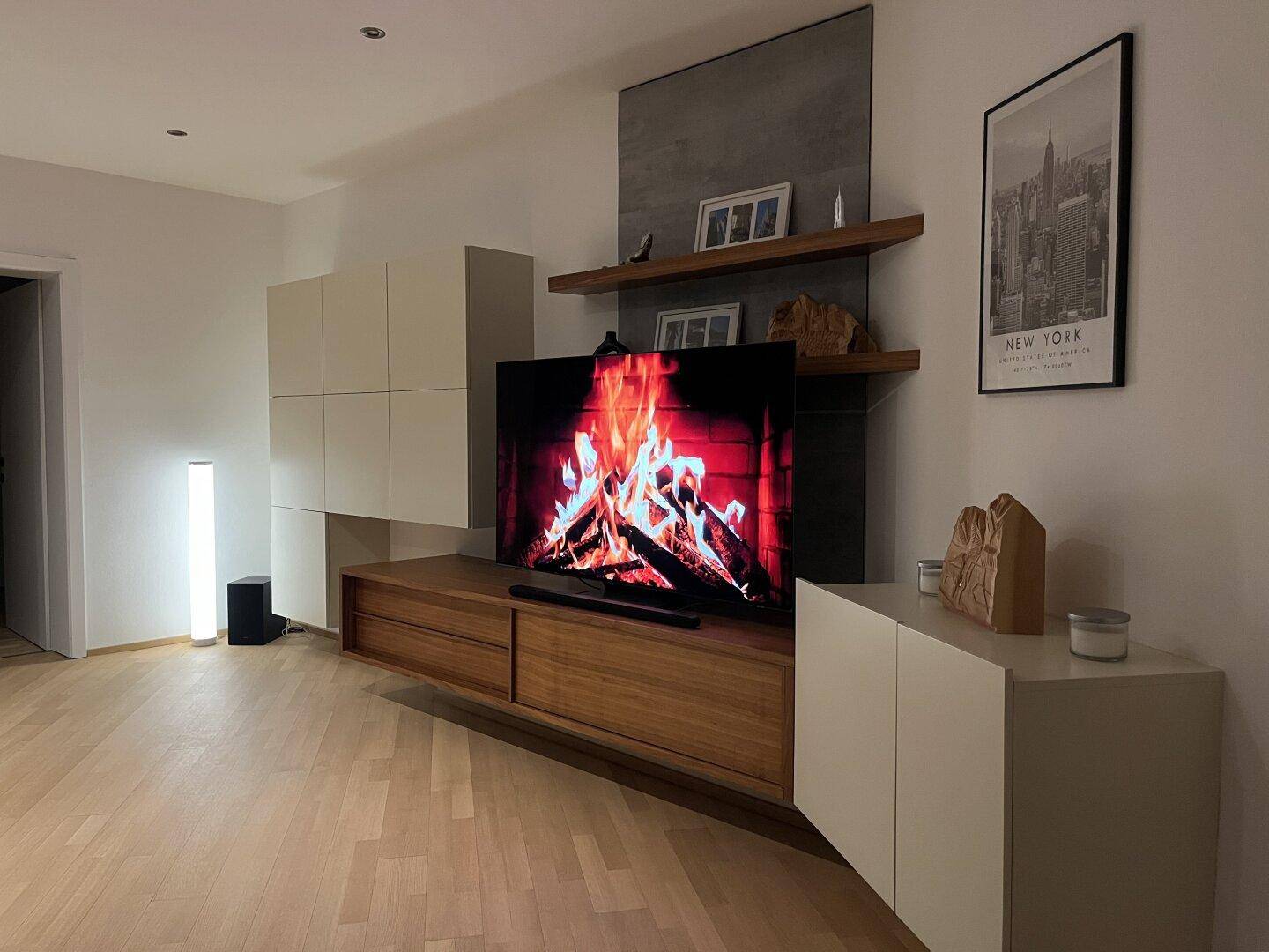 Modern eingerichtetes Wohnzimmer mit Holzboden, TV-Wand und indirekter Beleuchtung.
