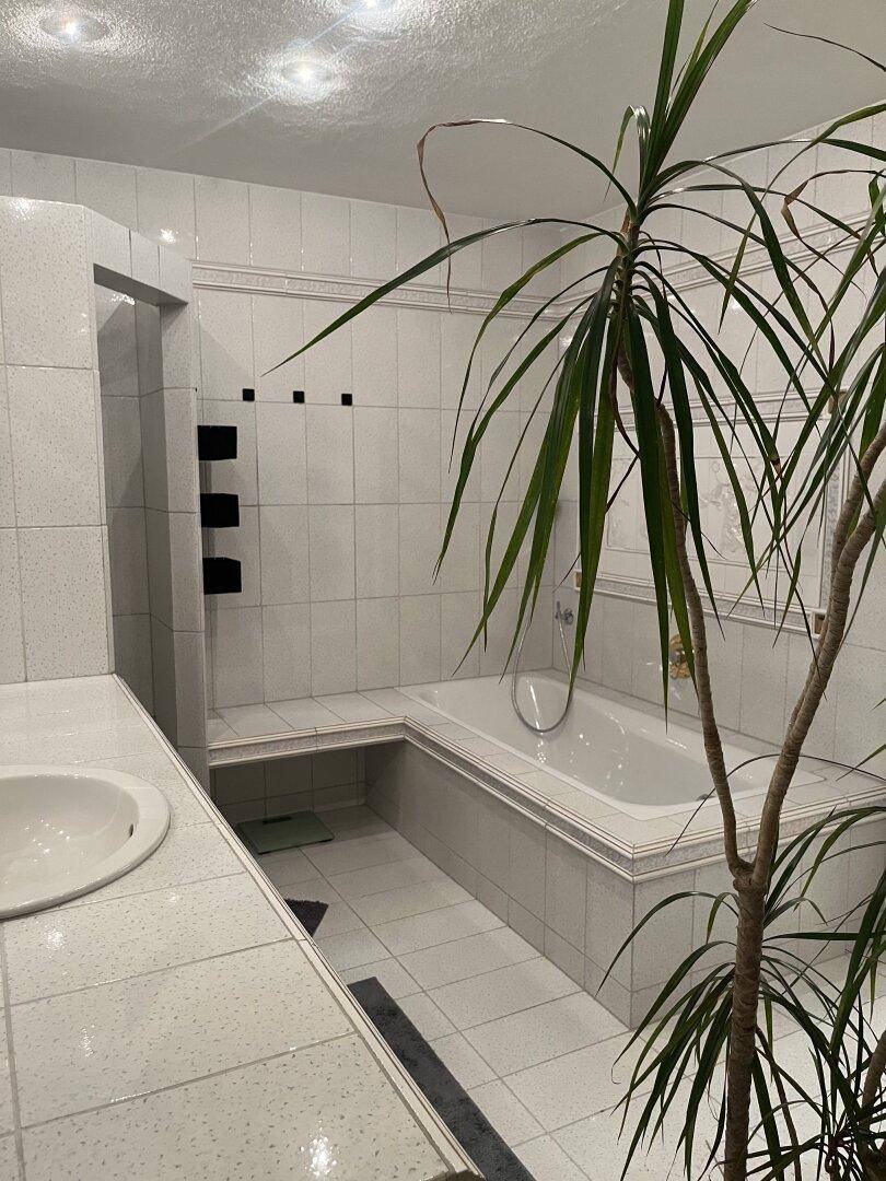 Geräumiges Badezimmer mit Badewanne, Dusche und weißen Fliesen.