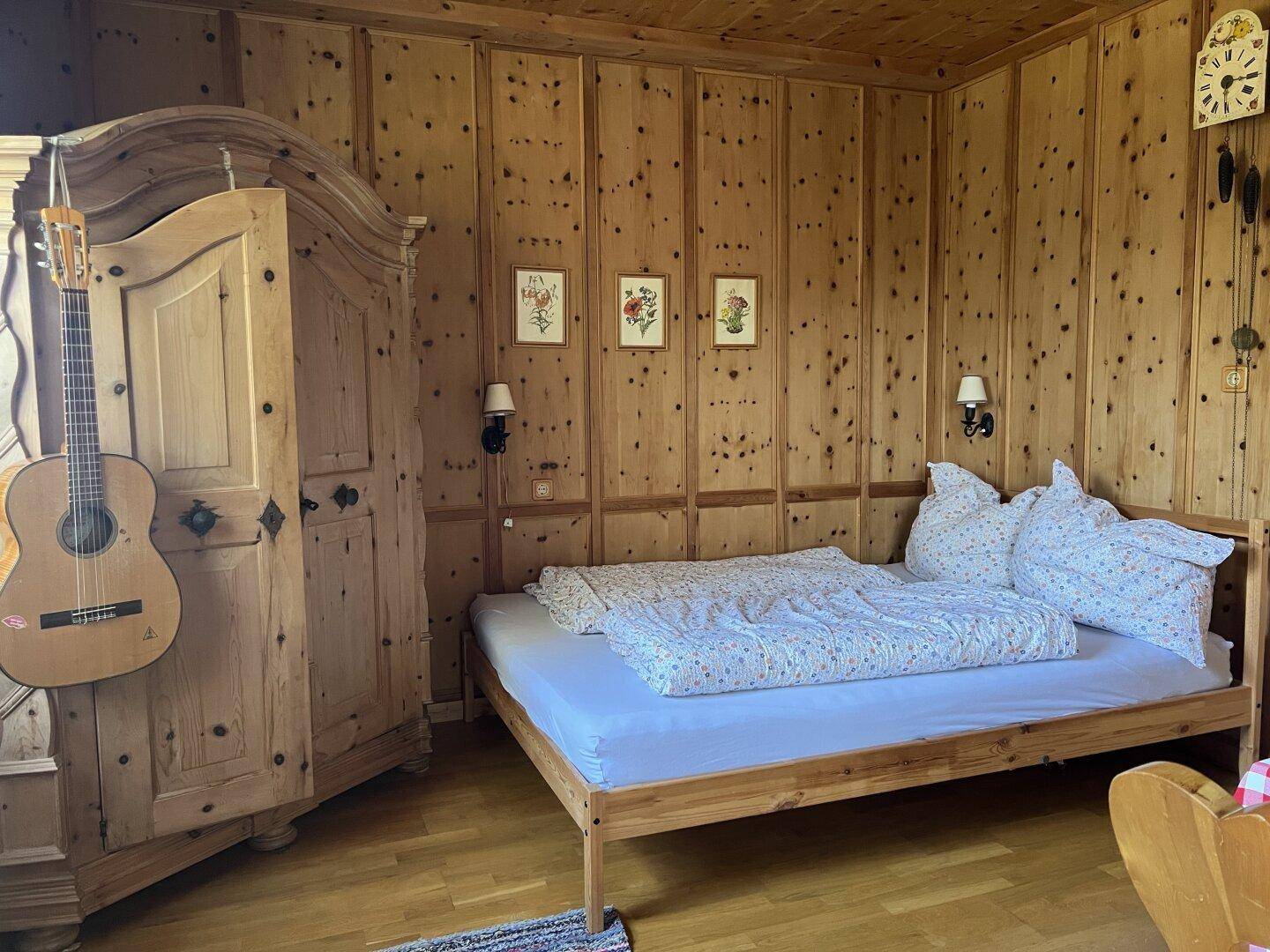 Gemütliches Schlafzimmer mit Holztäfelung, traditionellem Bett und rustikalem Kleiderschrank.