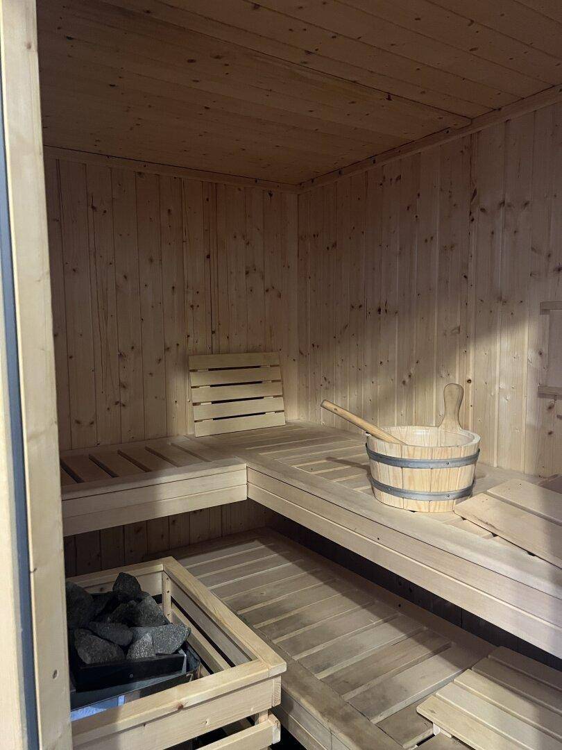 Helle Holzsauna mit Bänken und Saunaofen für entspannende Momente.