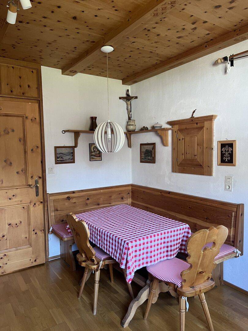 Rustikaler Essbereich mit Holzbänken, karierter Tischdecke und Holzdecke.