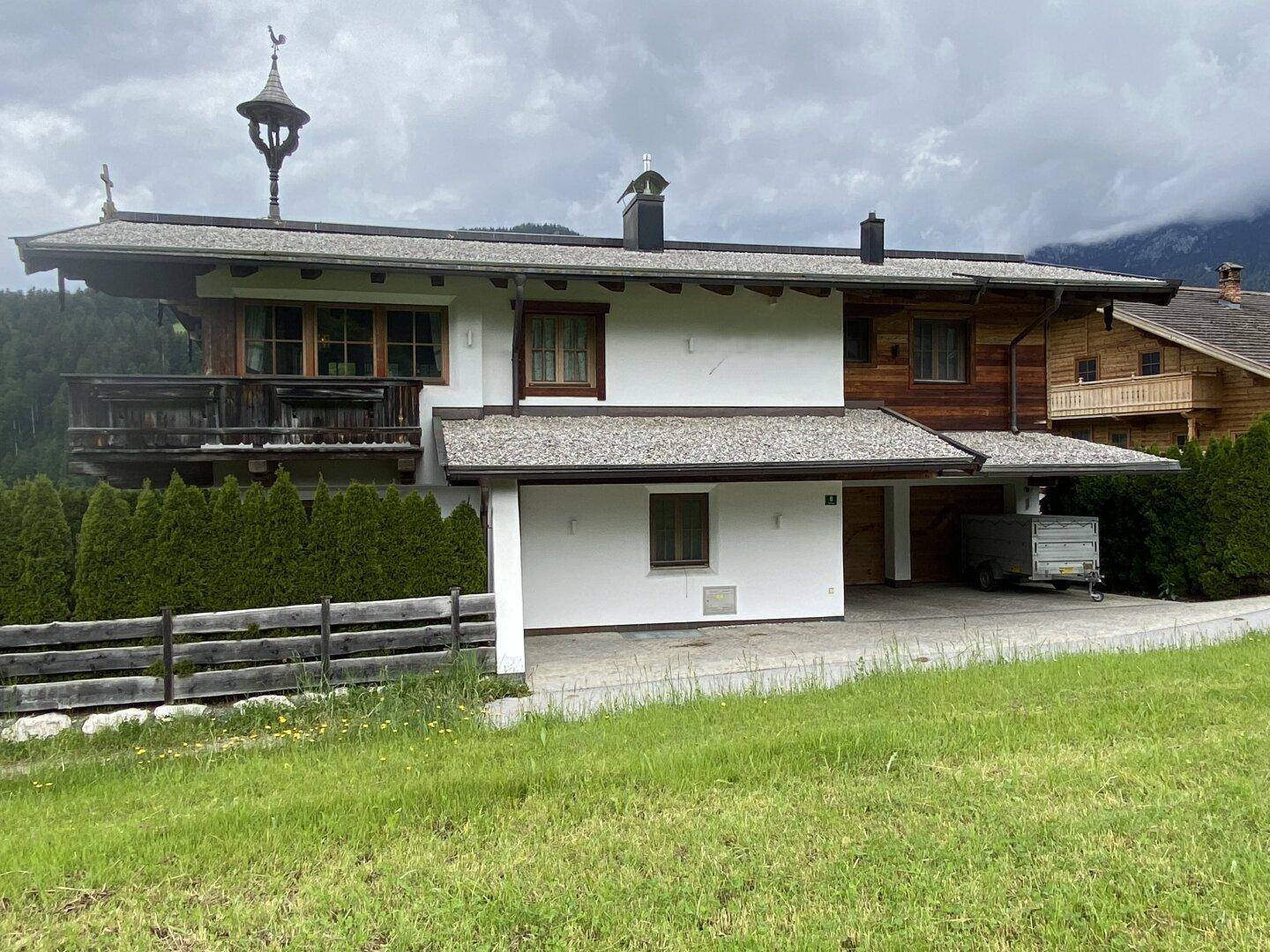 Vorderansicht des Chalets mit weißer Fassade, Holzdetails und einem überdachten Carport.