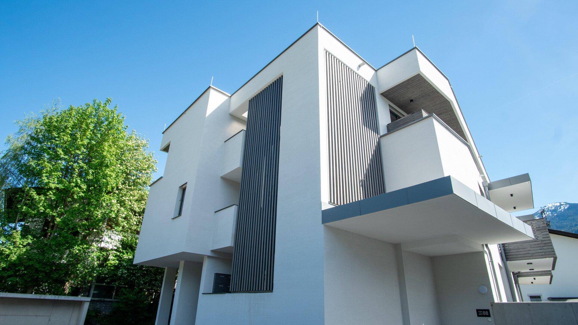 Seitenansicht eines modernen Wohnhauses mit klaren Linien und vertikalen Holzlamellen.