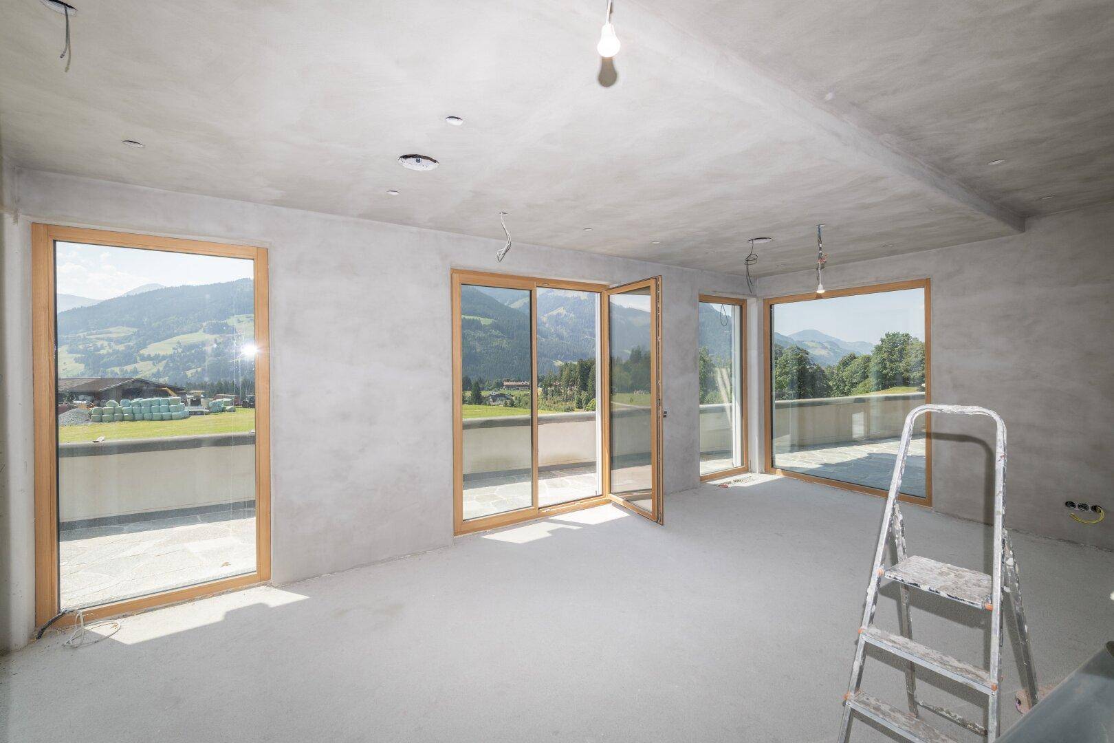 Heller Rohbau mit Betonwänden und großen Fenstern, die einen weiten Blick bieten.