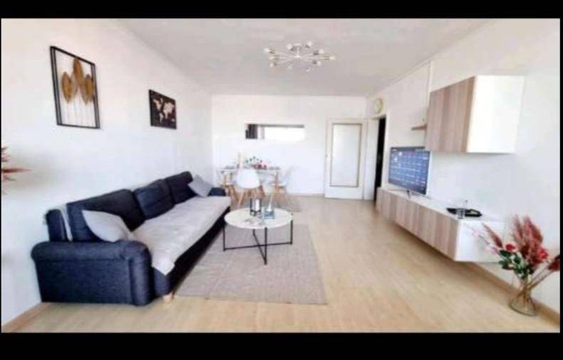 Heller Wohn- und Essbereich mit modernem Sofa, Laminatboden und schwebenden Möbeln.