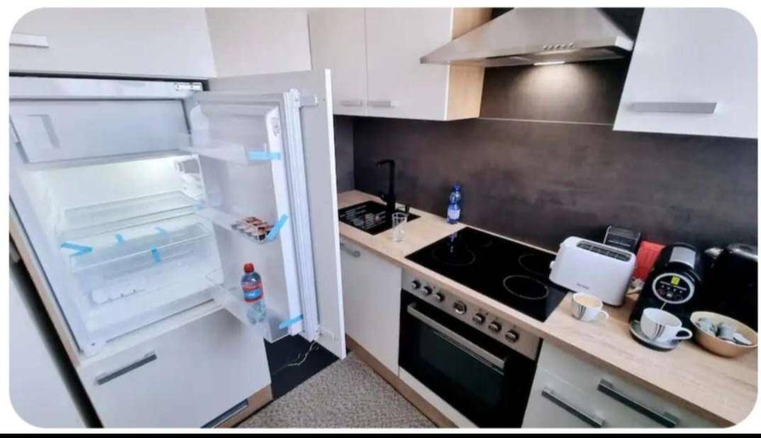 Moderne Einbauküche mit Kühlschrank, Induktionskochfeld und hellen Holz-Arbeitsplatten.