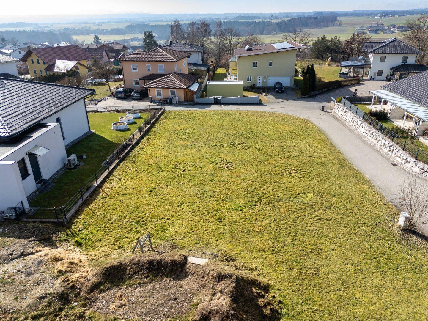Blick auf ein unbebautes Grundstück in einer ruhigen Wohngegend mit Fernsicht.