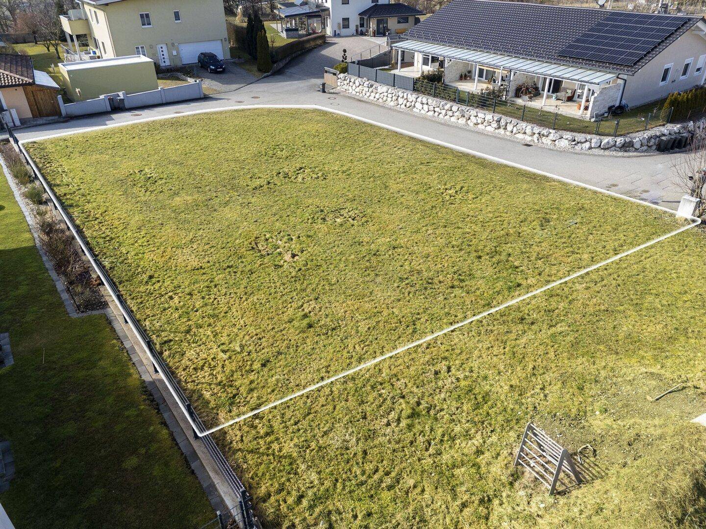 Großes, grünes Baugrundstück in sonniger Lage, umgeben von bestehenden Wohnhäusern.