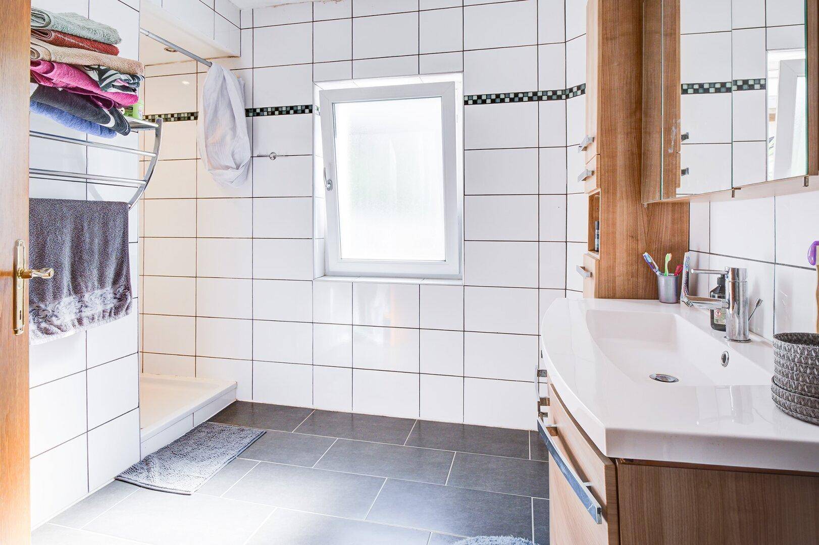 Modernes Badezimmer mit ebenerdiger Dusche, Einzelwaschbecken und weißen Fliesen.