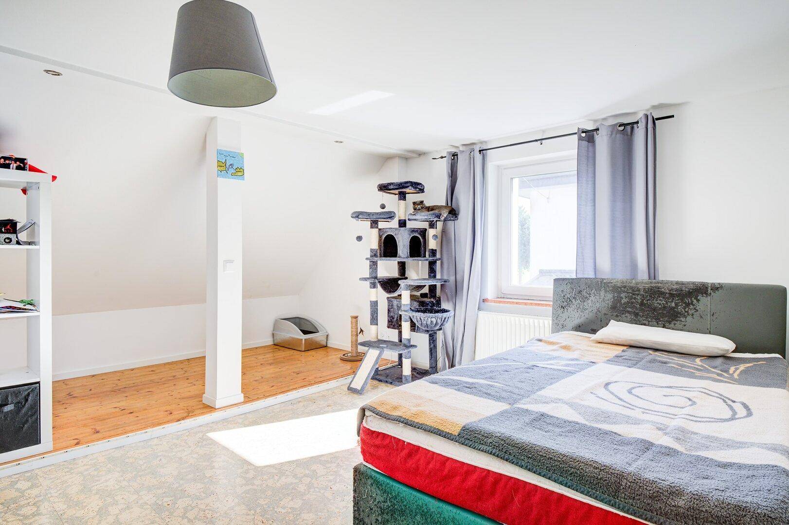 Gemütliches Schlafzimmer im Dachgeschoss mit Dachschräge und Fenster.