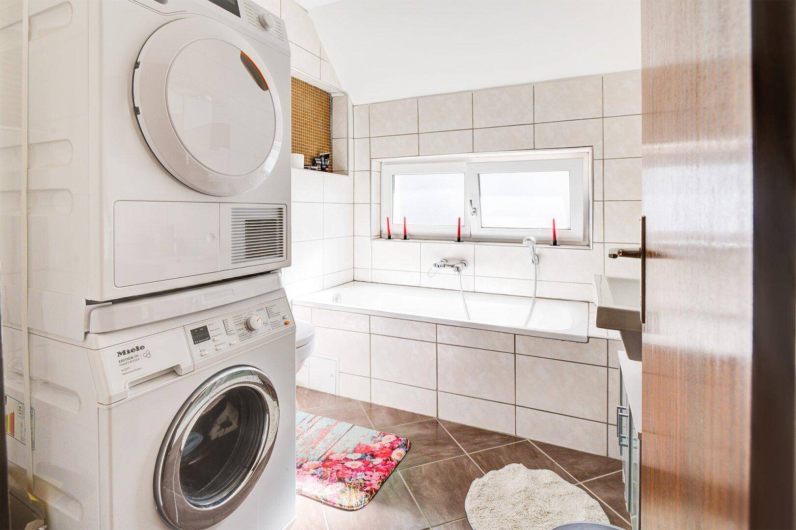 Badezimmer mit Badewanne, Waschmaschine und Trockner.