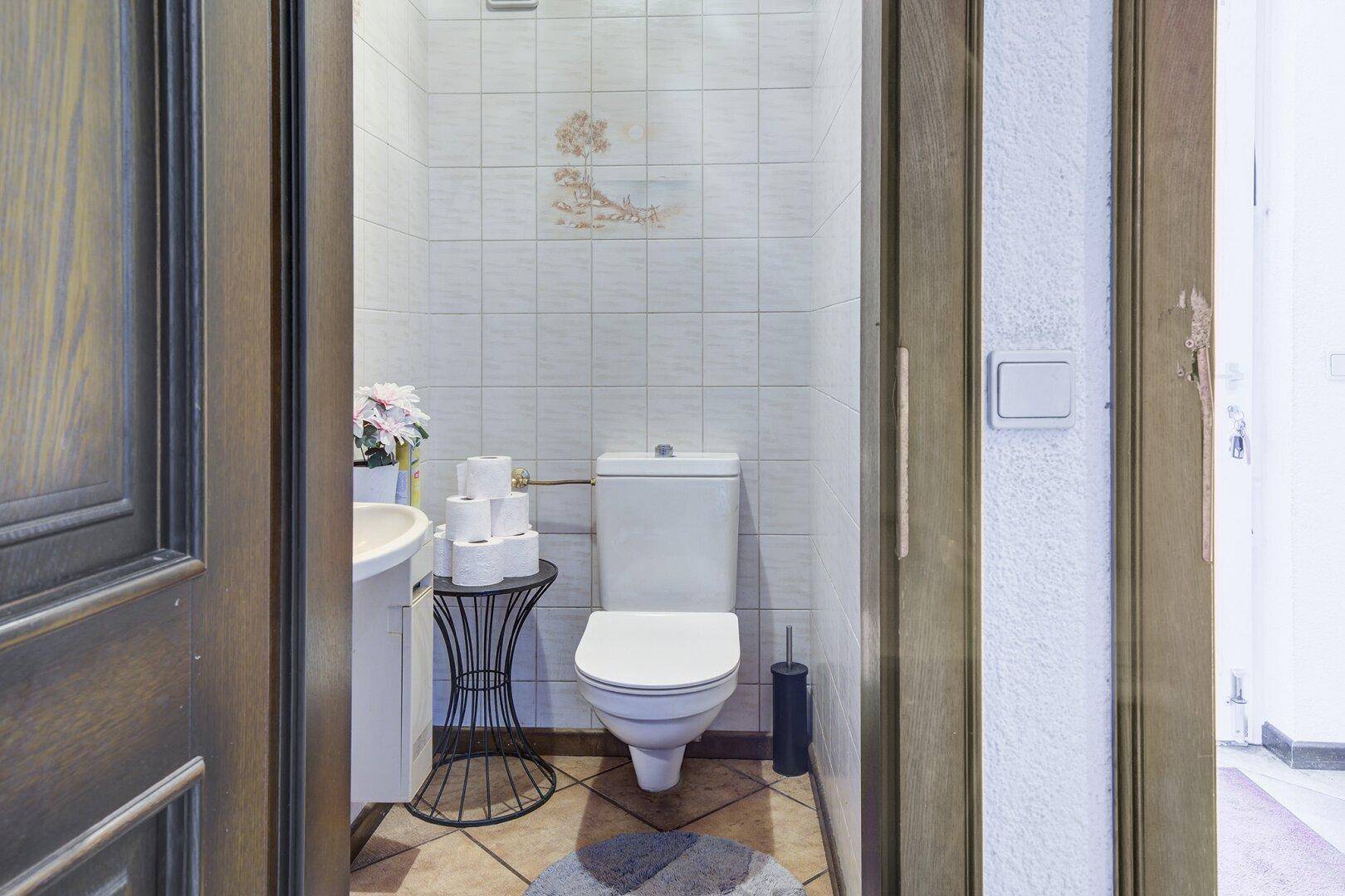 Kleines Gäste-WC mit WC und Waschbecken, hell gefliest und praktisch eingerichtet.