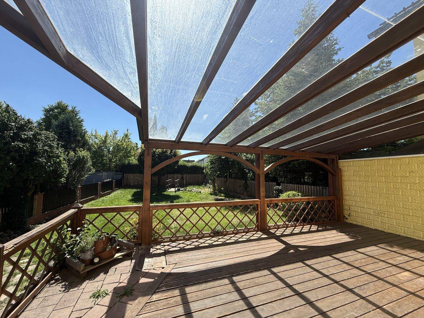 Überdachte Holzterrasse mit Blick auf den Garten, ideal für entspannte Stunden im Freien.