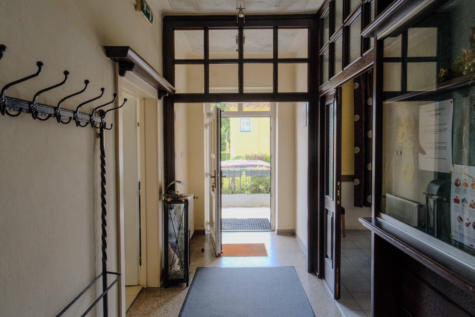 Eingangsbereich mit Garderobe und Blick durch die offene Tür ins Freie.