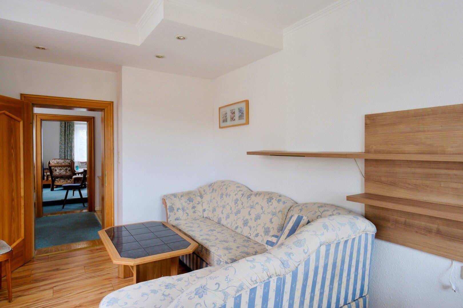 Wohnzimmer mit gestreiftem Sofa, Holzboden und dekorativen Wandregalen.