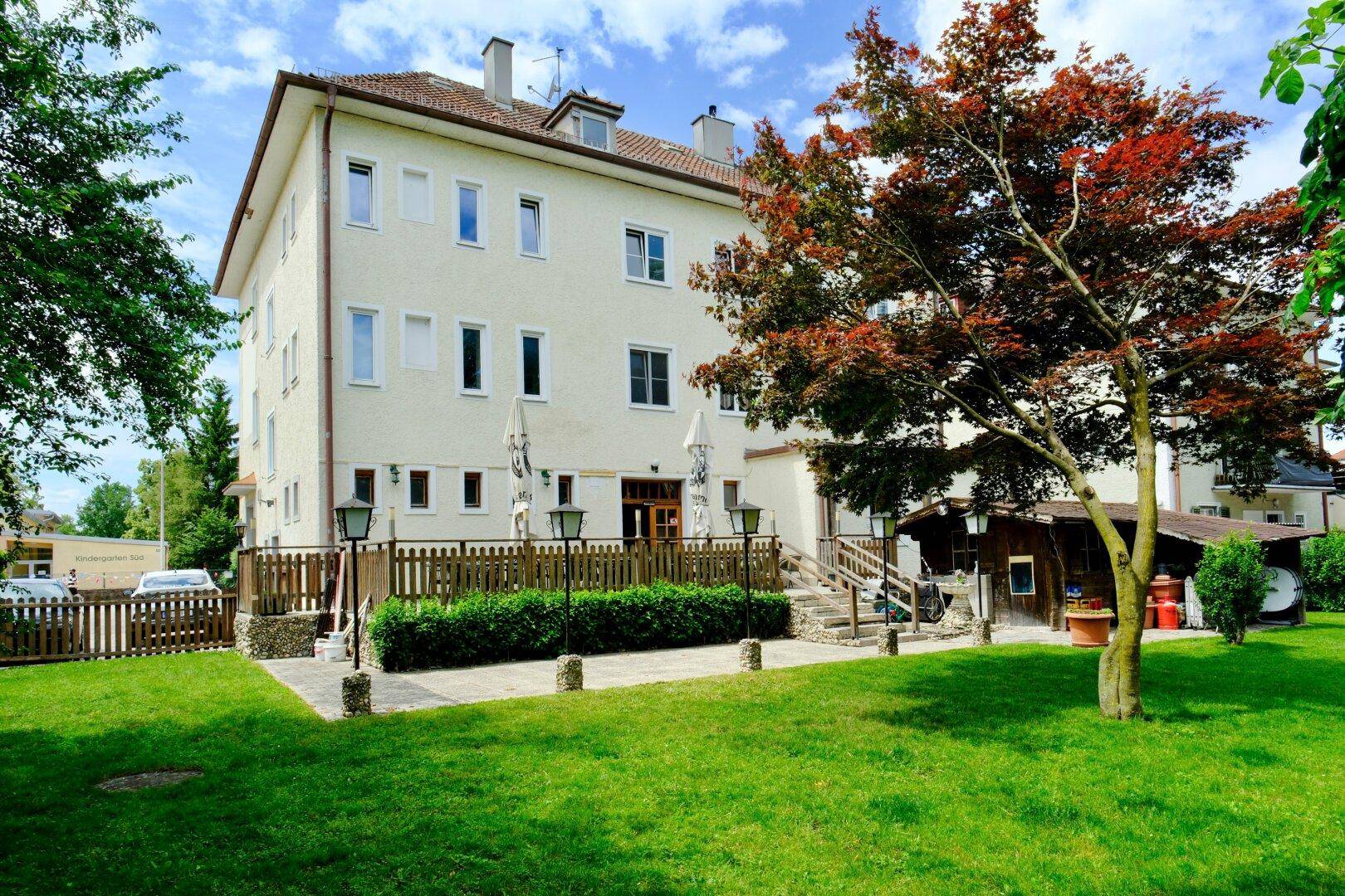 Außenansicht des Gebäudes mit gepflegtem Garten, Terrasse und dekorativen Laternen.