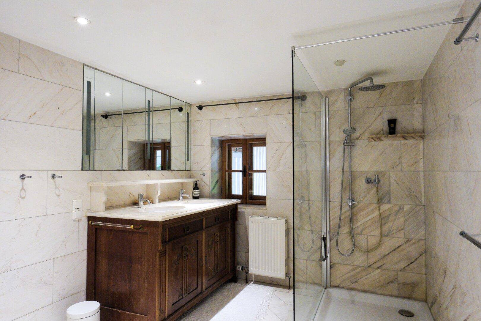 Modernes Badezimmer mit Marmorfliesen, Doppelwaschbecken und großer begehbarer Dusche.
