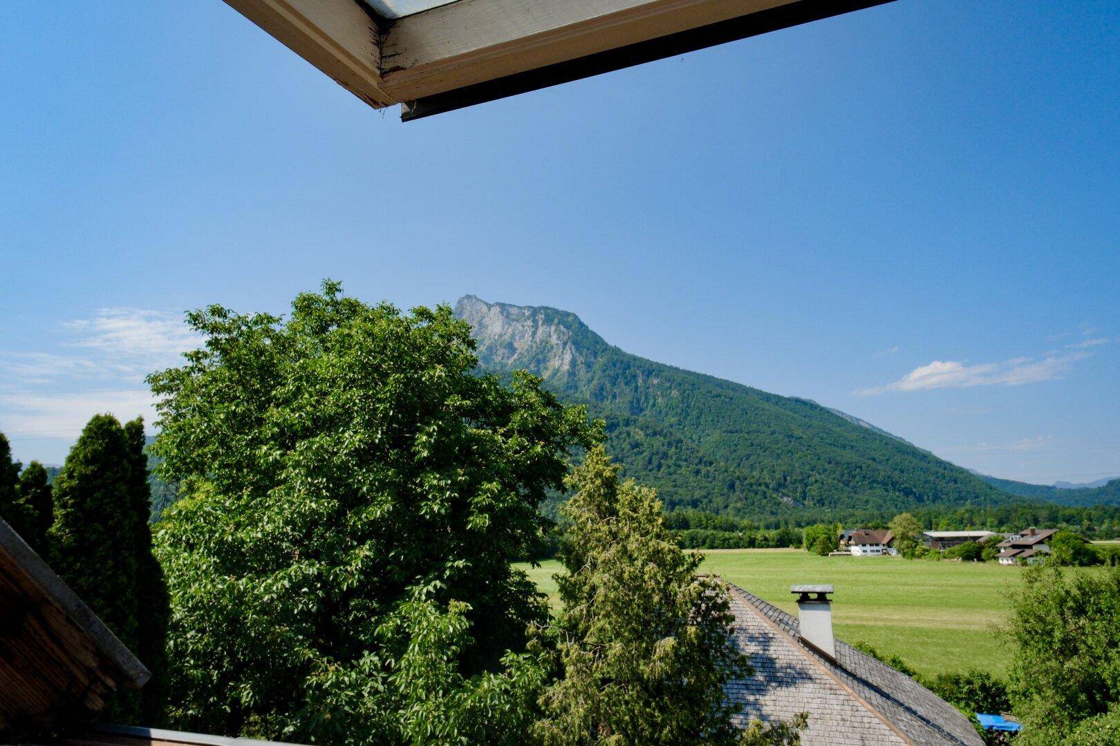 Weitläufiger Blick auf die majestätischen Berge und die grüne Landschaft unter blauem Himmel.
