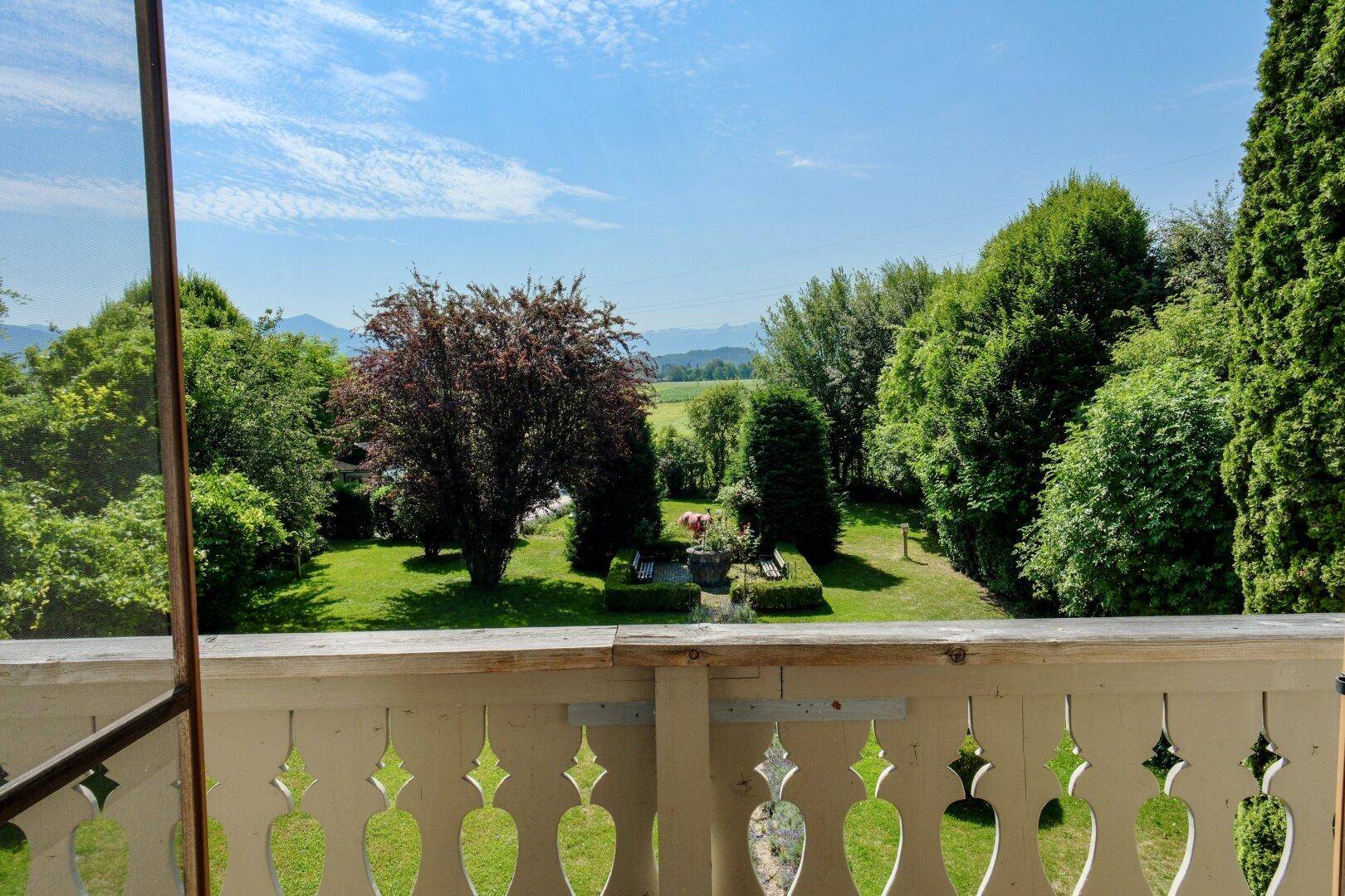 Malerischer Ausblick vom Balkon auf die grüne Landschaft und die umliegenden Berge.
