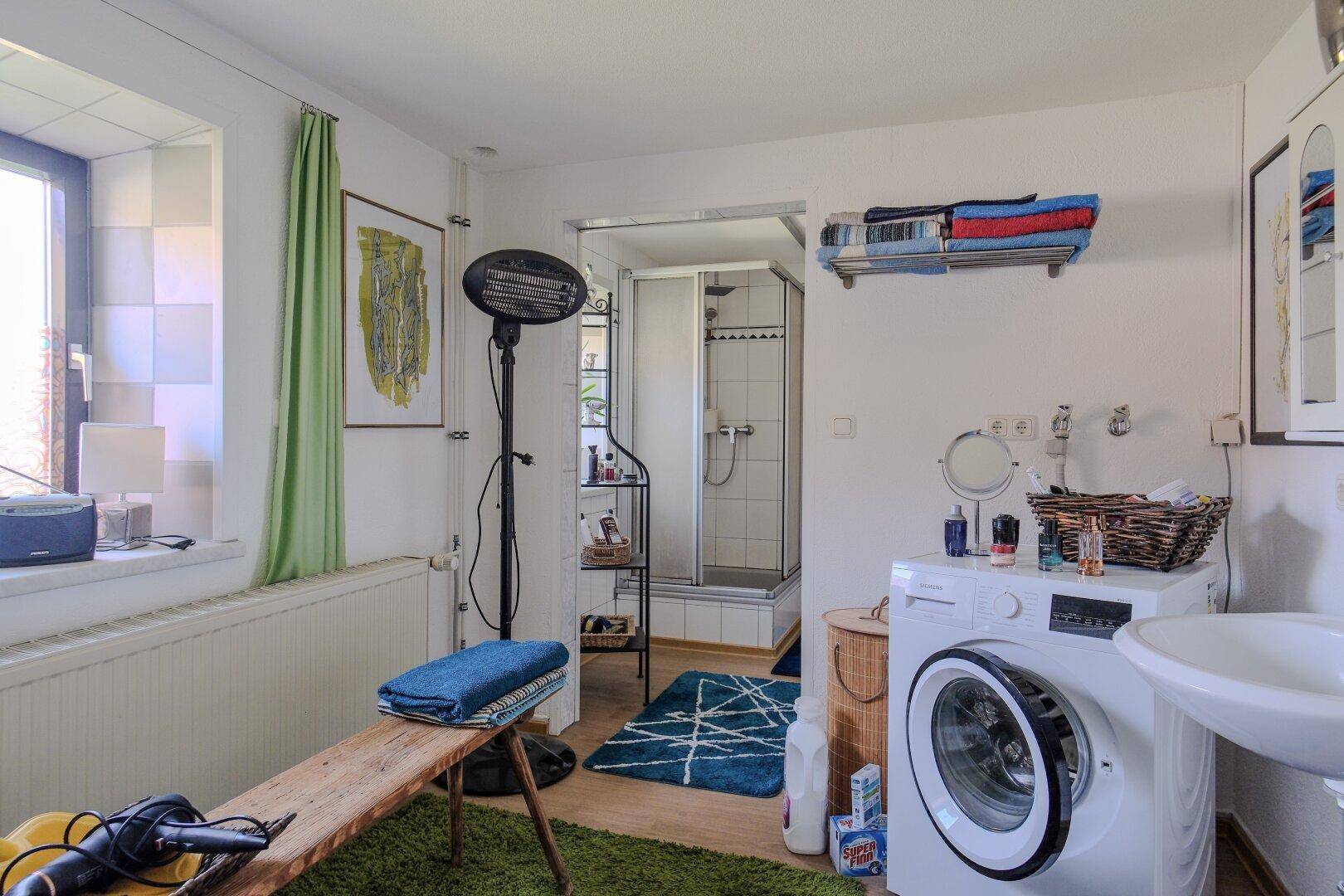 Badezimmer mit Waschmaschine, Dusche und Fenster für natürliche Belüftung.
