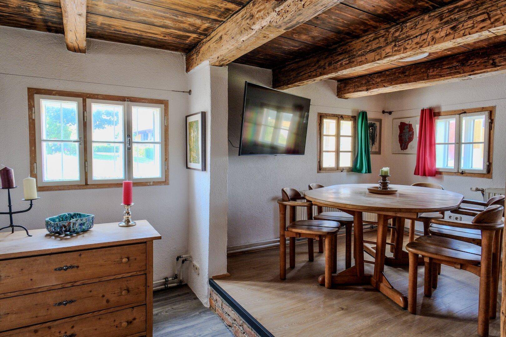Essbereich mit rustikalem Holztisch, passenden Stühlen und einem Fernseher an der Wand.