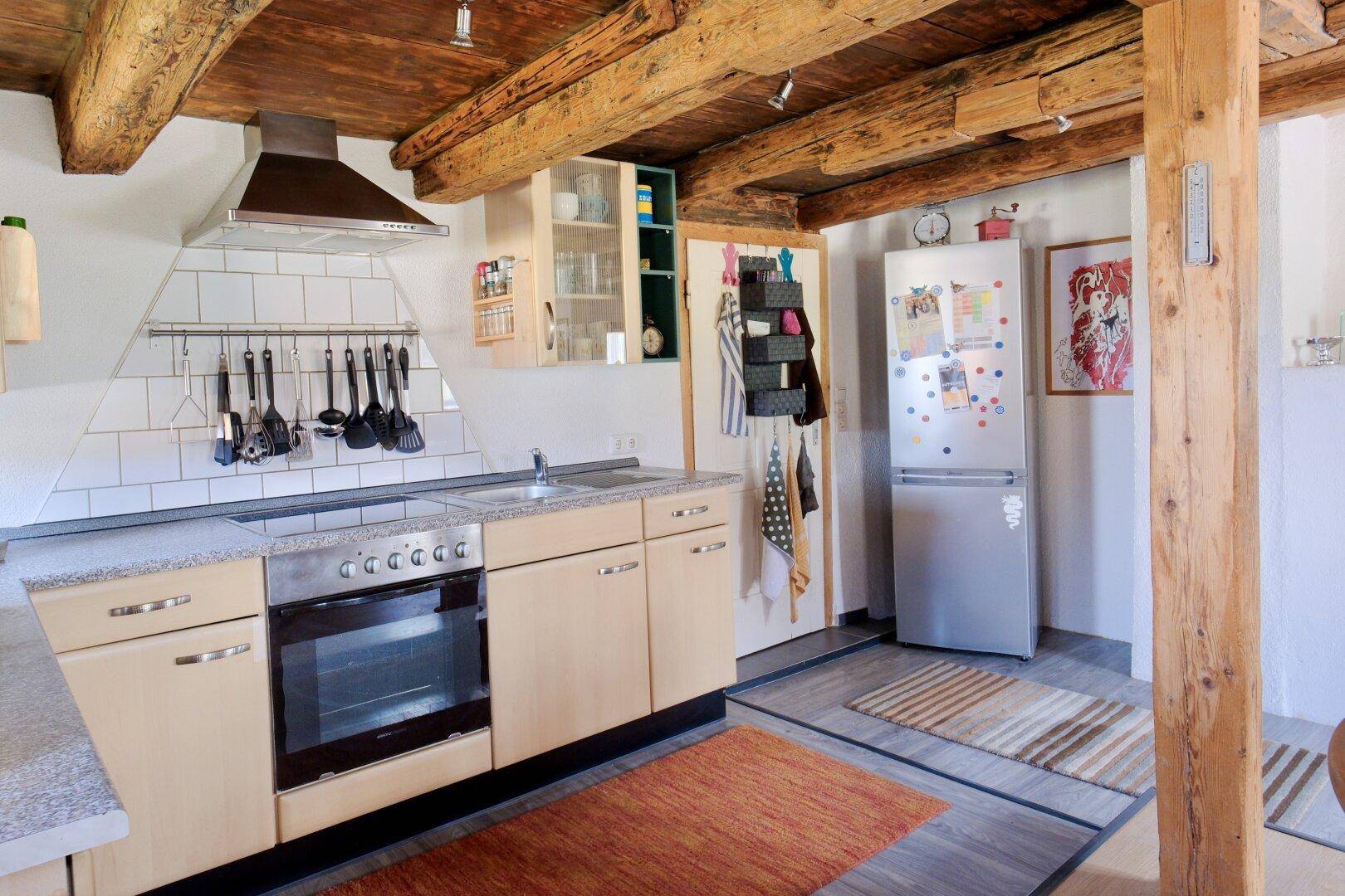 Geräumige Küche mit Holzbalkendecke, Kühlschrank und viel Stauraum.