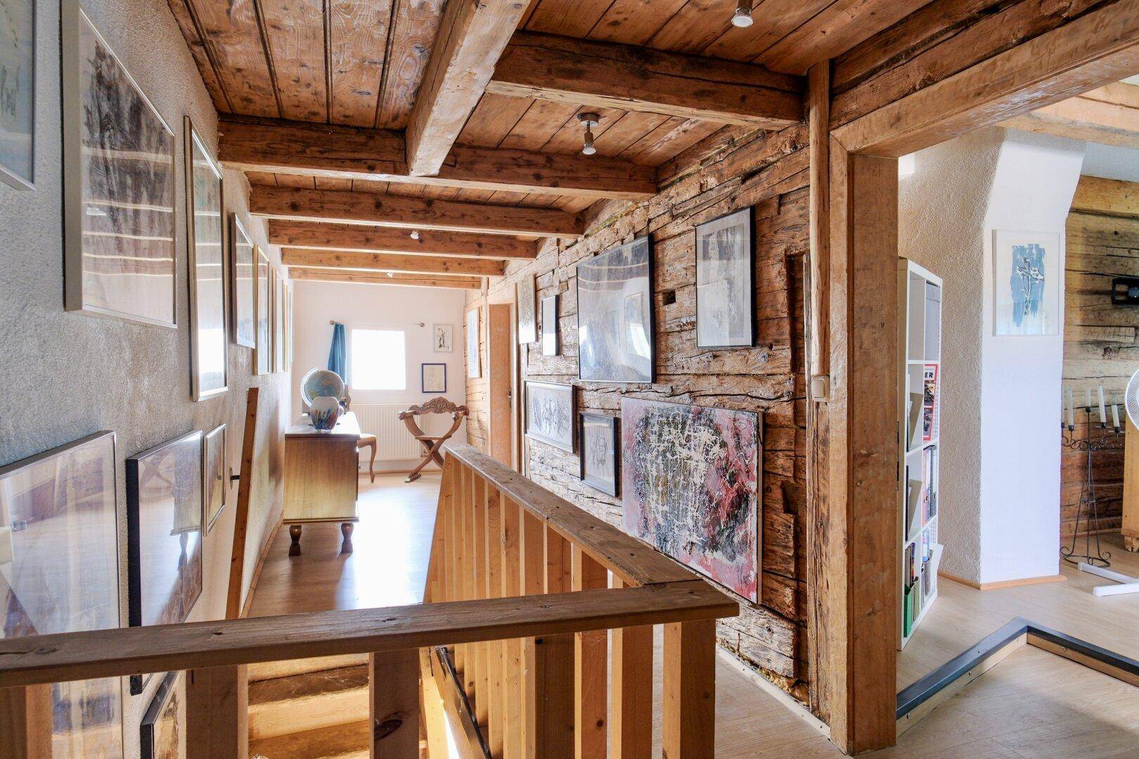 Treppenhaus mit Holzbalken, rustikalen Holzwänden und vielen gerahmten Bildern.
