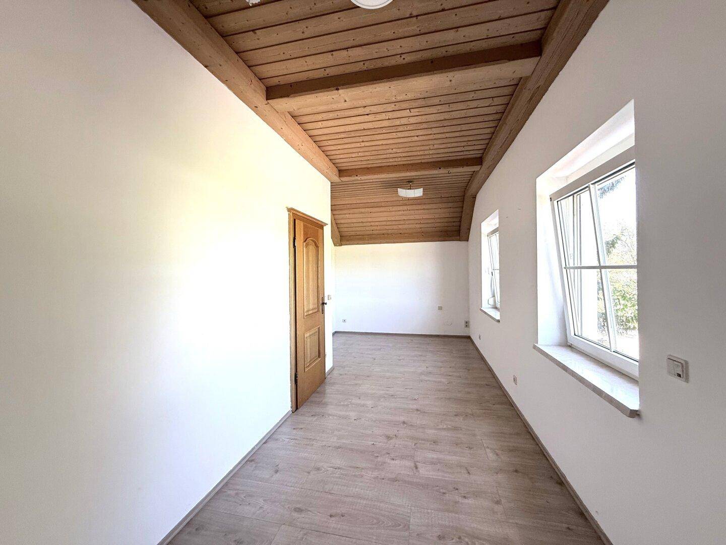 Helles Zimmer mit Holzbalkendecke und Laminatboden, bietet vielseitige Nutzungsmöglichkeiten.
