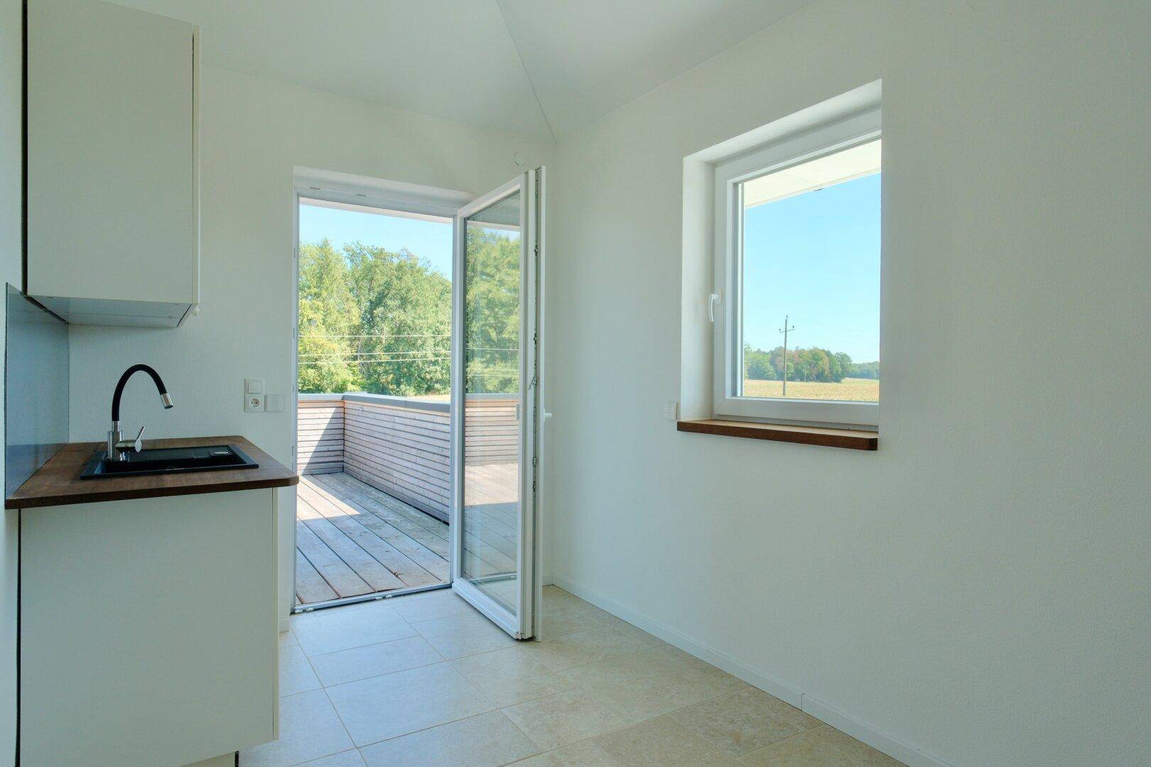 Kleine Küche mit Spülbecken, Fenster und direktem Zugang zur Dachterrasse.