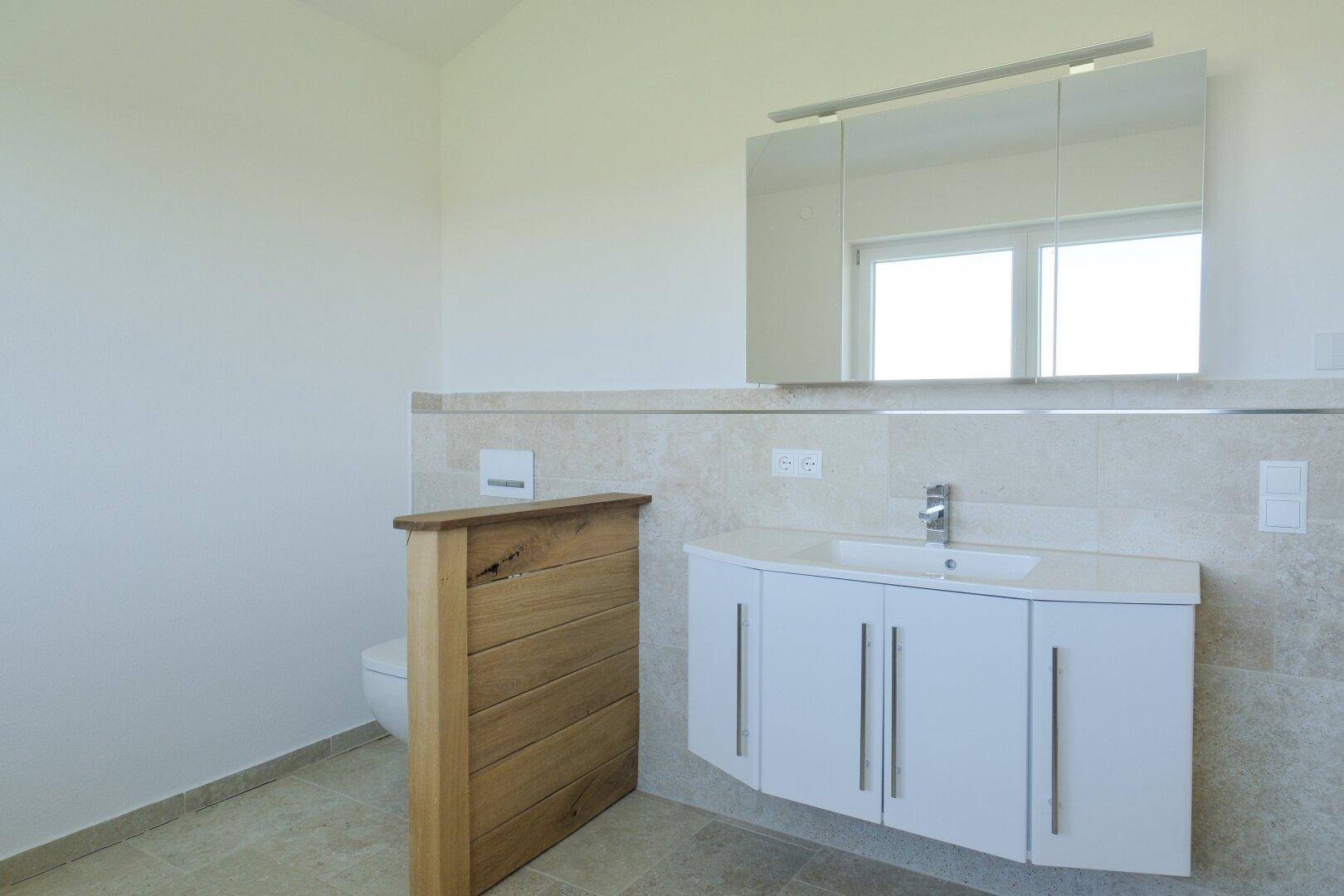 Modernes Badezimmer mit weißem Waschtischunterschrank, Einzelwaschbecken und Spiegelschrank.