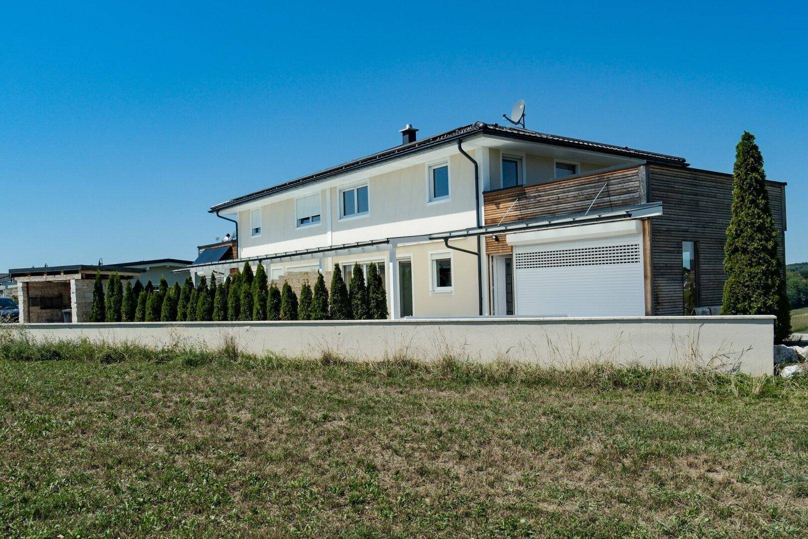 Modernes Einfamilienhaus mit Holzfassade und weitem Blick über die Landschaft.