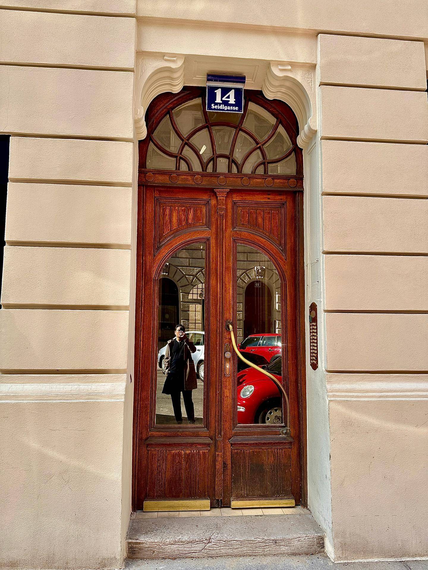 Historische Holztür mit Glaspaneelen und Hausnummer 14 in einem eleganten Gebäude.