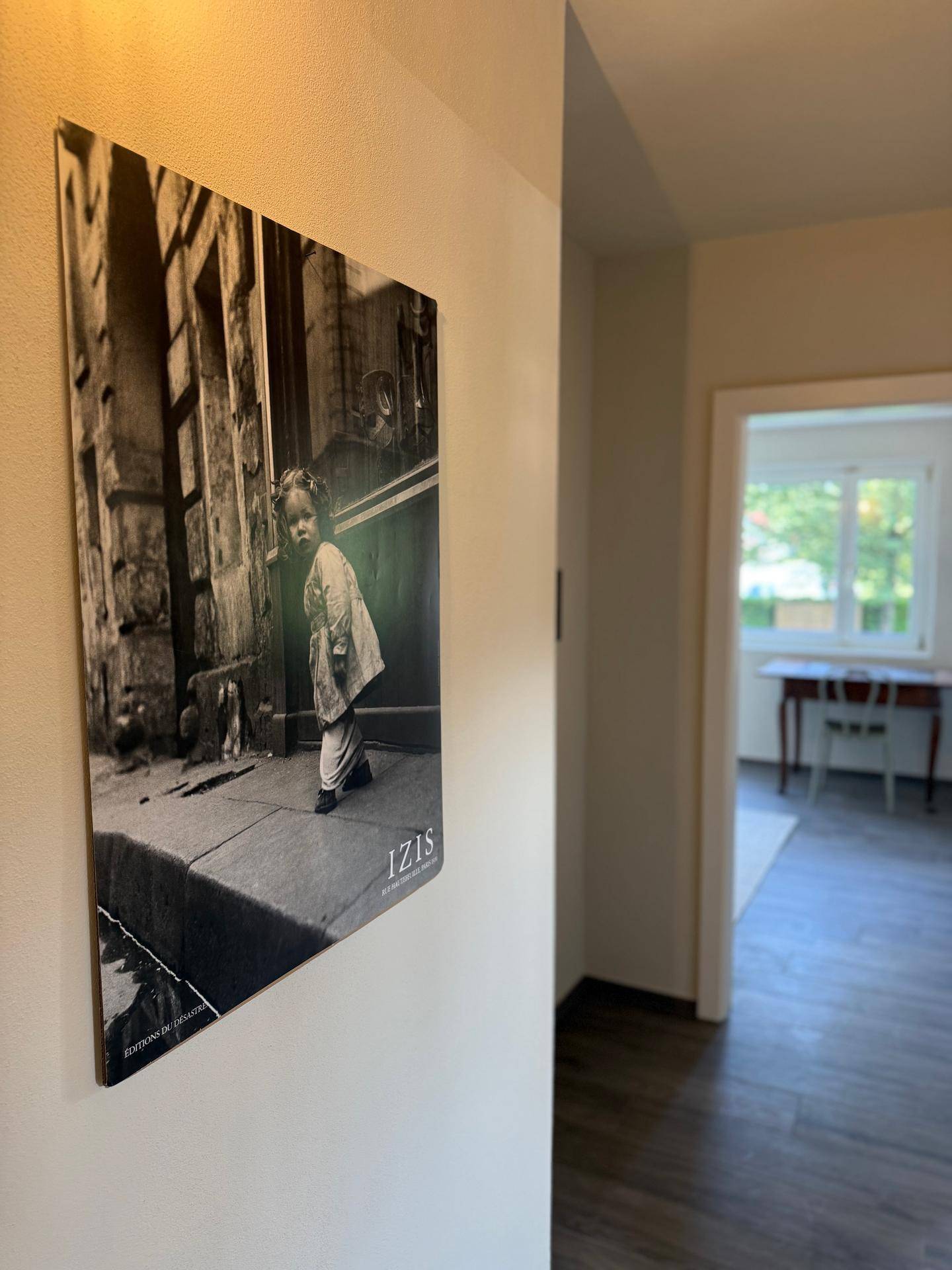 Flur mit Holzboden und einem Schwarz-Weiß-Bild an der Wand, führt zu weiteren Räumen.