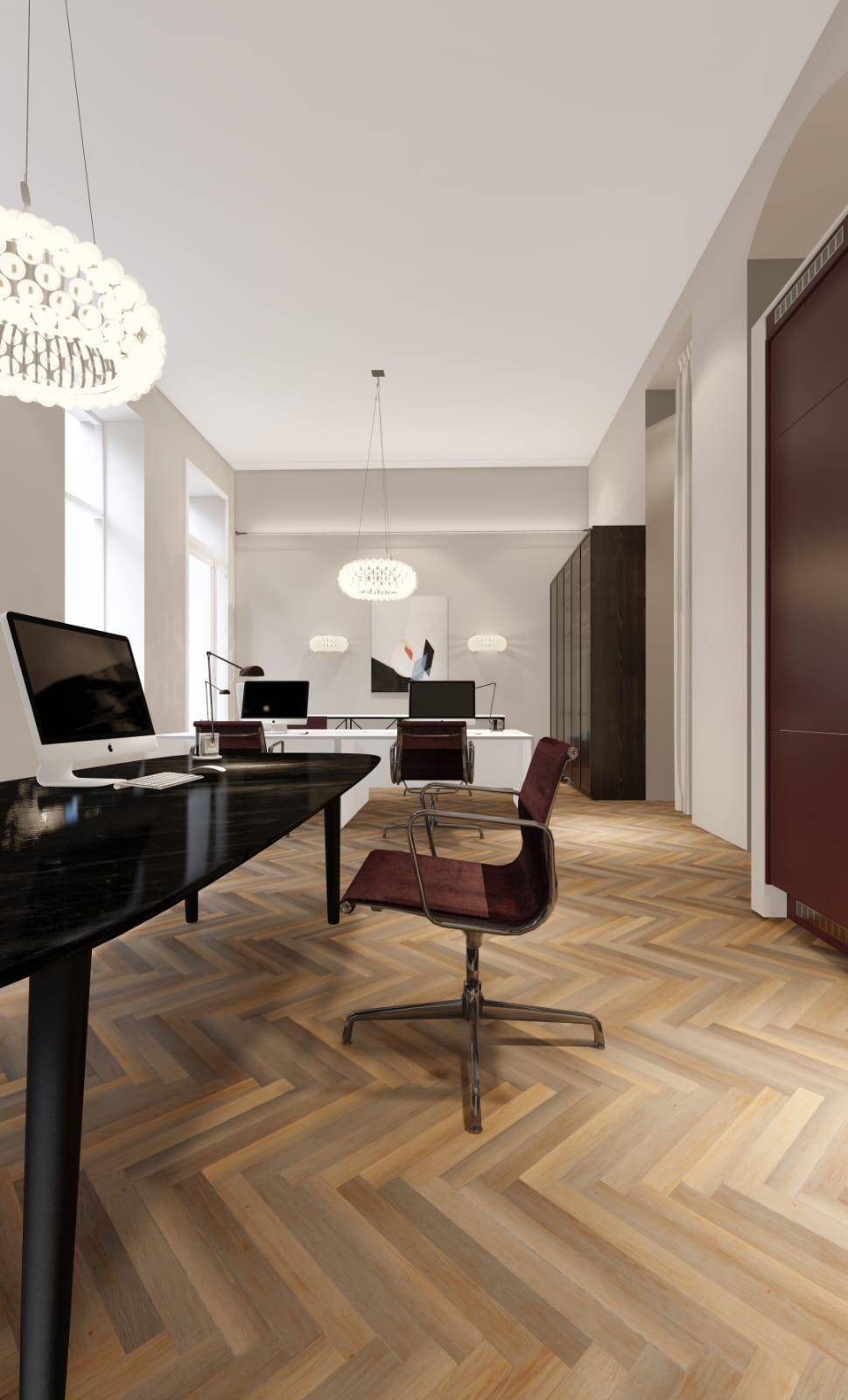 Großes, modernes Büro mit Fischgrätparkett, mehreren Arbeitsplätzen und hohen Decken.