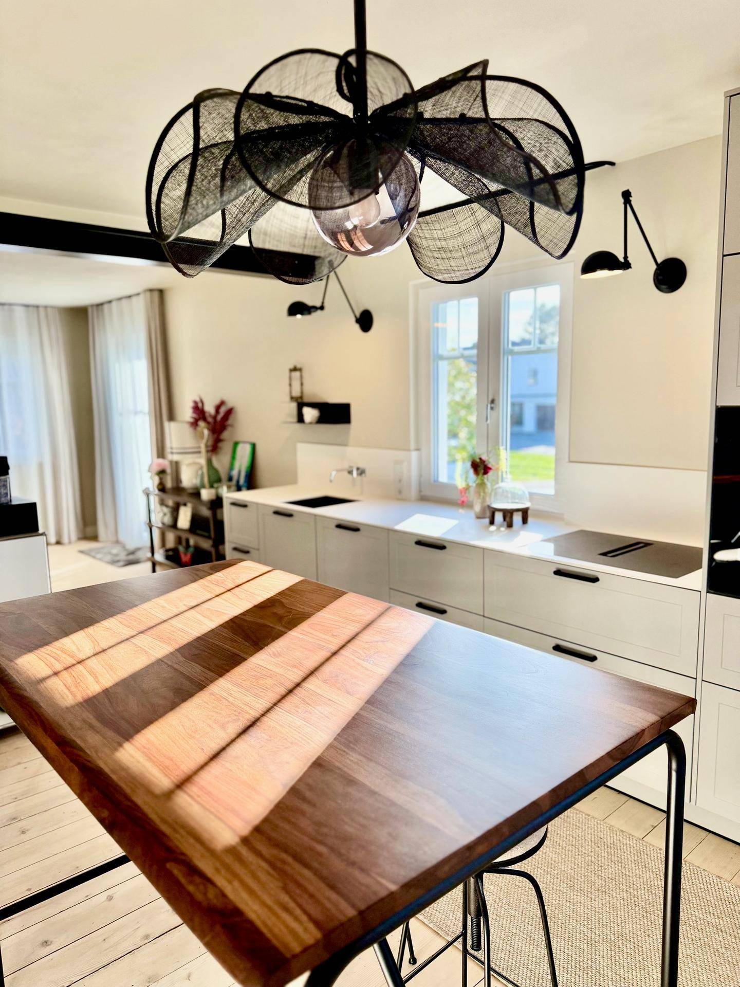 Offener Wohnbereich mit Bartisch und Blick auf die moderne, helle Küchenzeile.