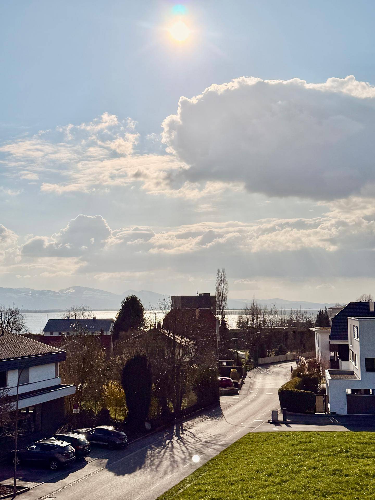 Panoramablick auf einen See und Berge unter einem sonnigen Himmel mit Wolken.
