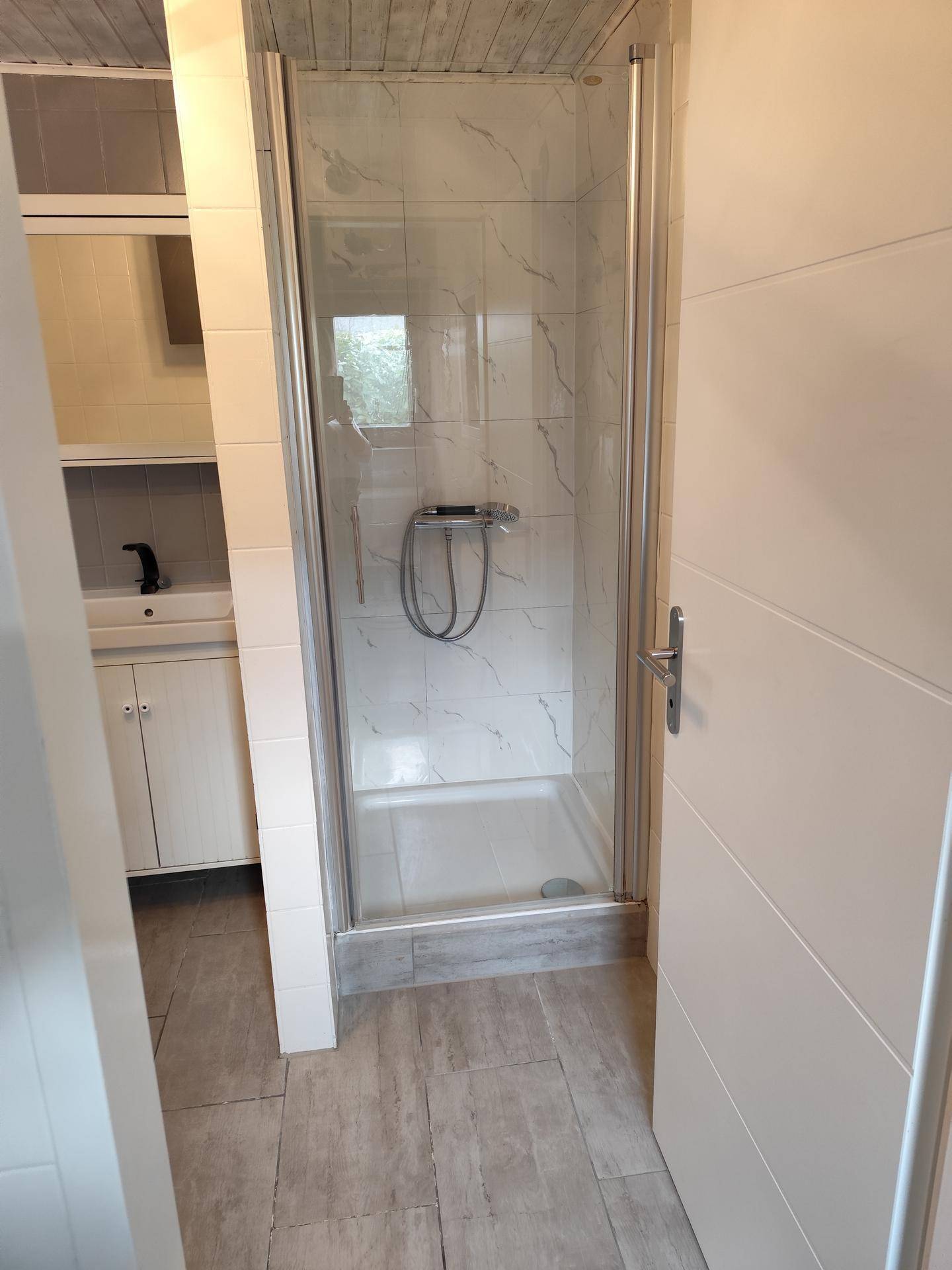 Modernes Badezimmer mit Duschkabine und hellen Fliesen, funktional und sauber.