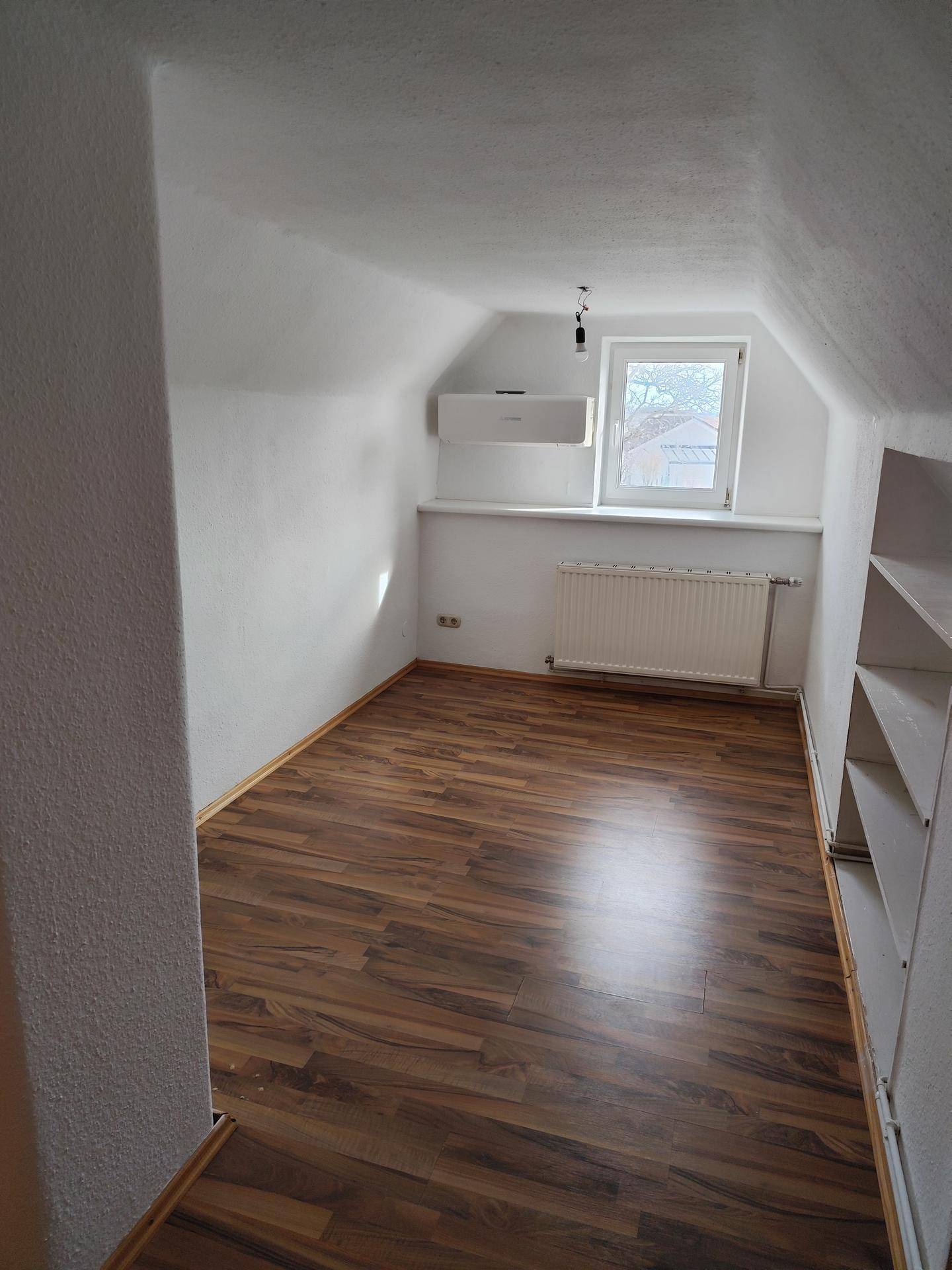 Gemütliches Schlafzimmer im Dachgeschoss mit Laminatboden und Dachschräge, hell und einladend.
