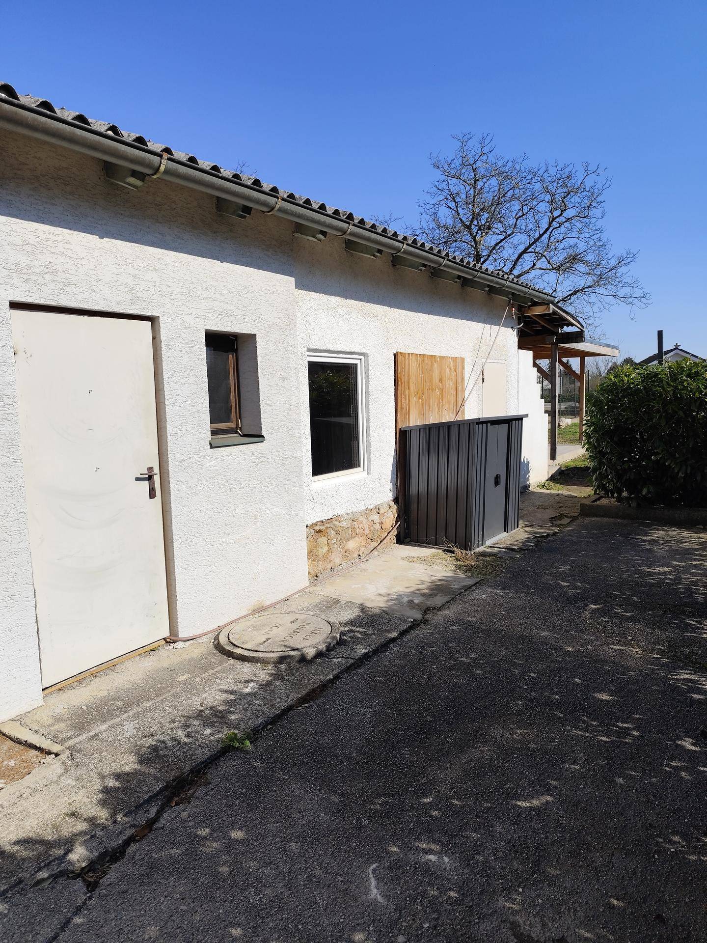 Seitenansicht des Hauses mit Nebeneingang und einem kleinen Geräteschuppen im Freien.