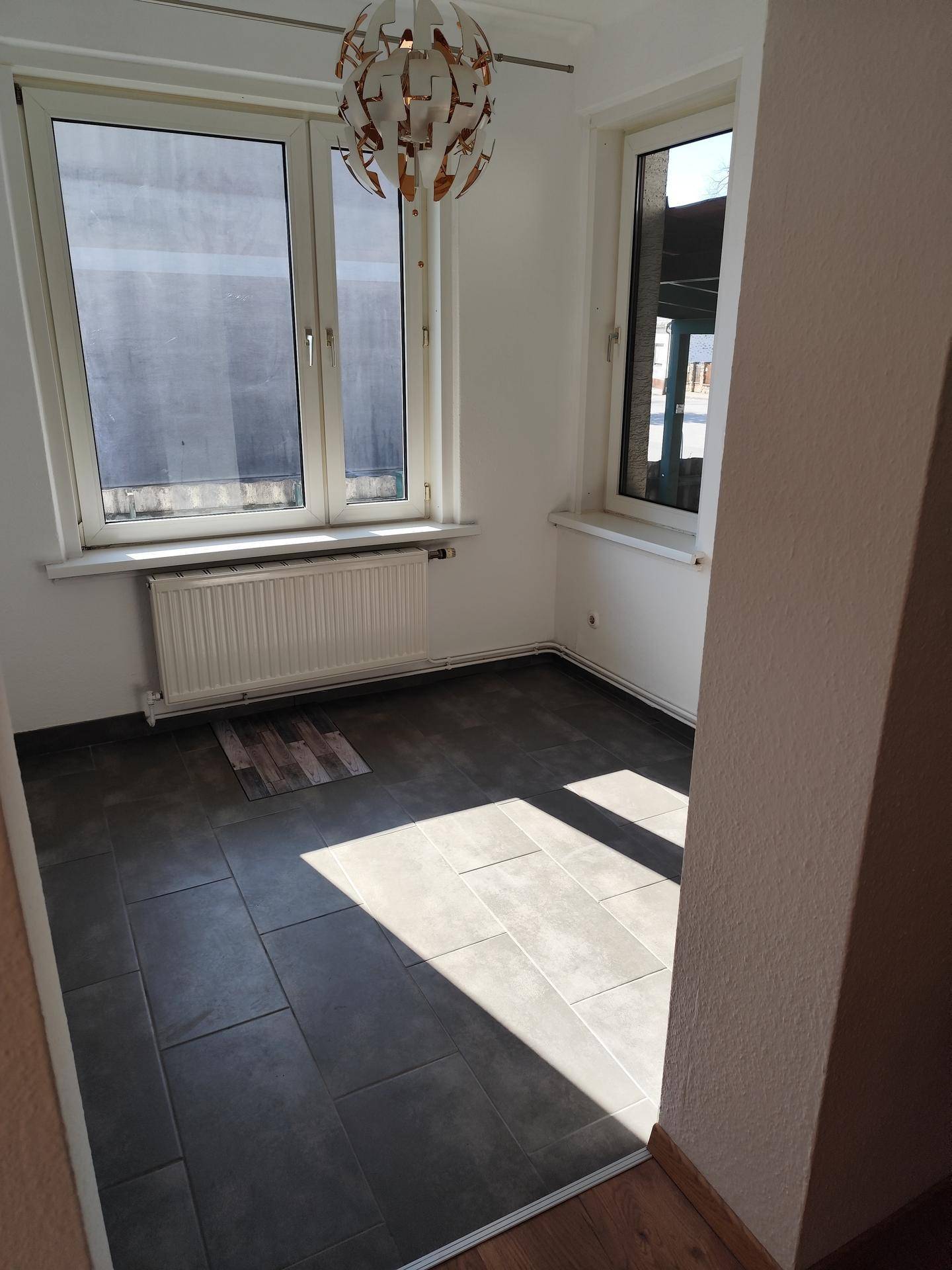 Heller Essbereich mit Fliesenboden und großen Fenstern, ideal für Tageslicht und gemütliche Mahlzeiten.
