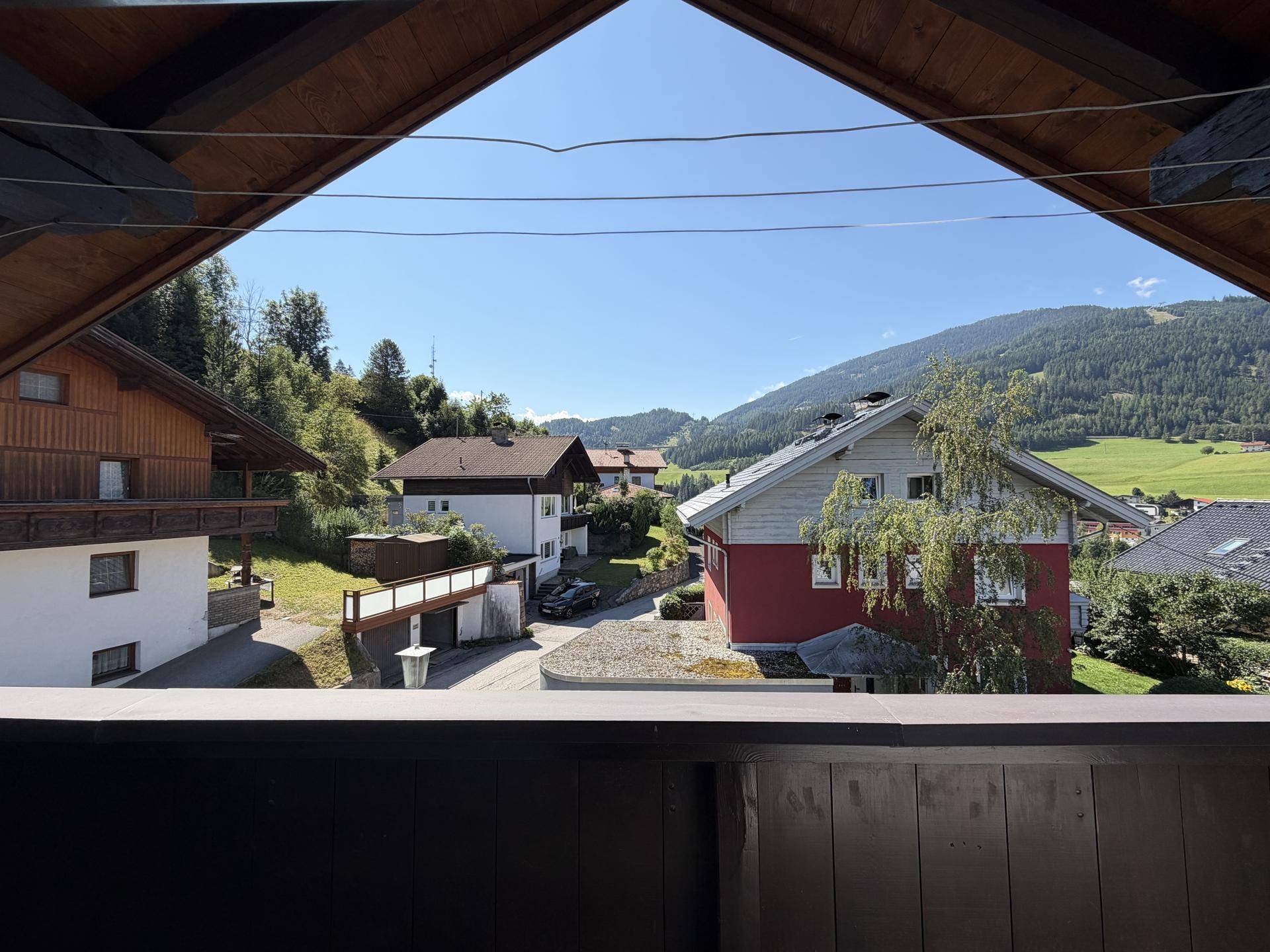 Panoramablick auf die grüne Berglandschaft und die umliegenden Häuser von oben.