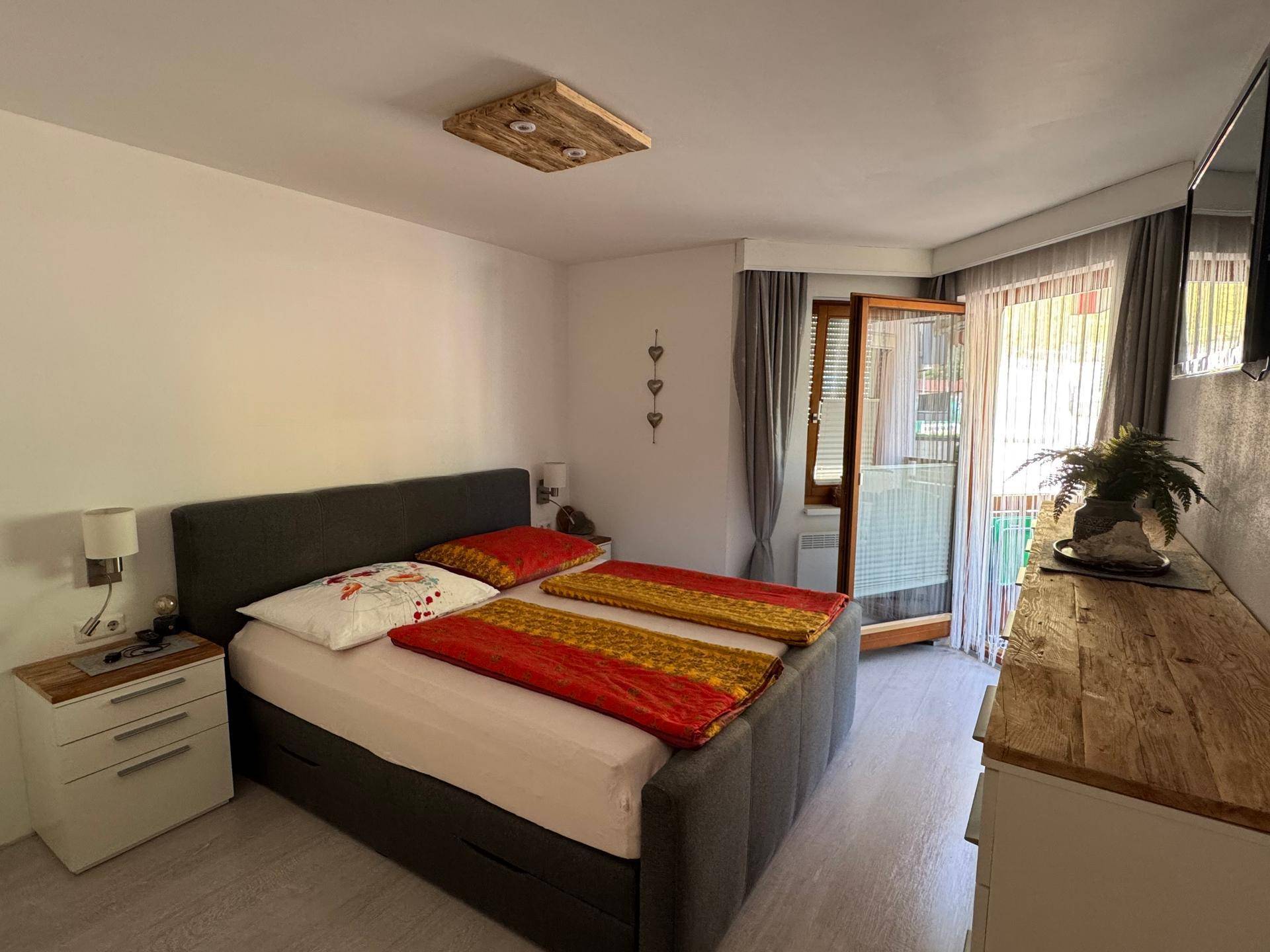 Gemütliches Schlafzimmer mit Doppelbett, Holzelementen und direktem Zugang zum Balkon.