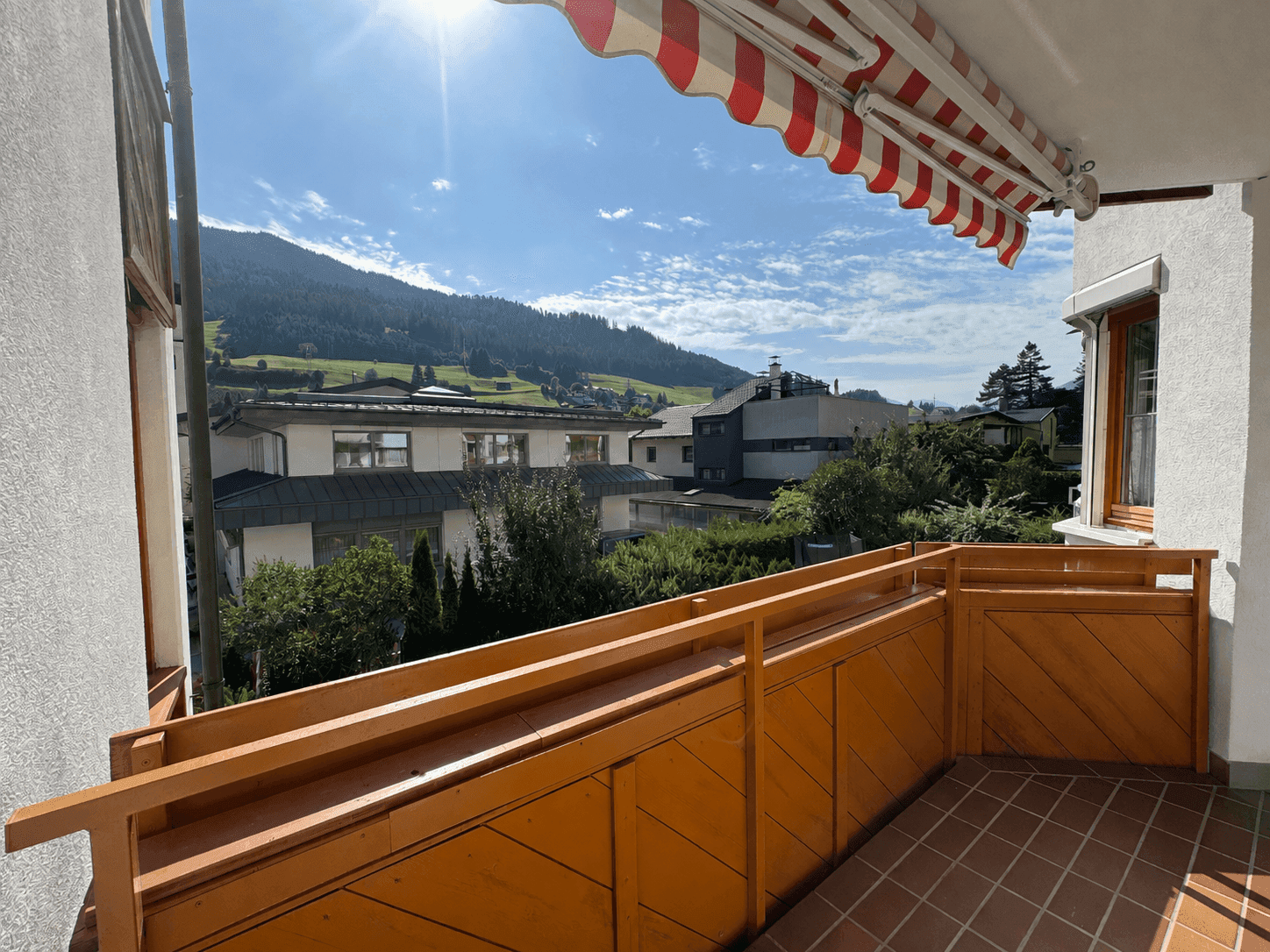 Sonniger Balkon mit Markise und weitem Blick auf die umliegende Berglandschaft.